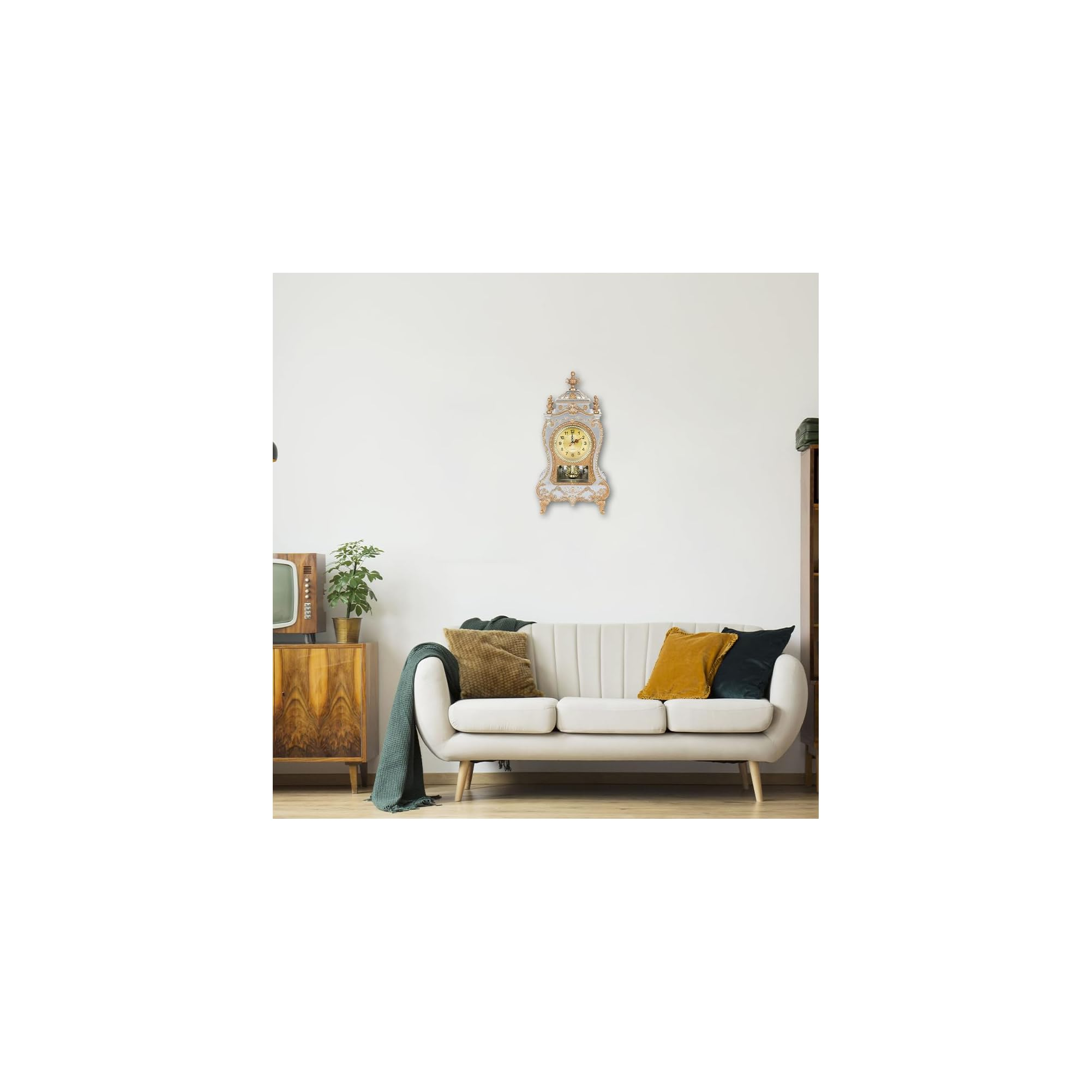 Wohnzimmer mit weißem Sofa, goldenen Kissen, verzierten Wanduhr, Holzkommode und Pflanze.