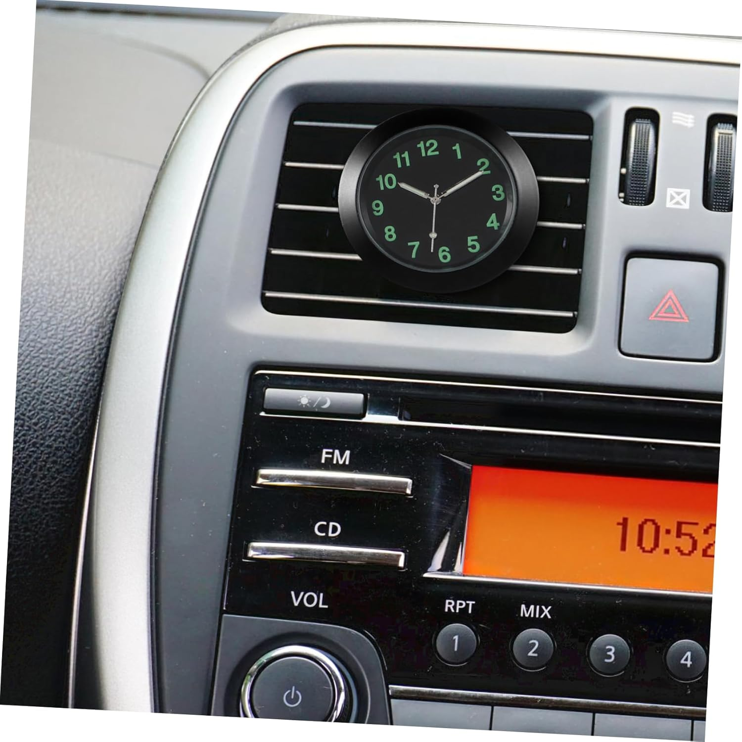 Eine kleine runde Uhr mit grünem Zifferblatt ist an den Lüftungsschlitzen des Autos angebracht.