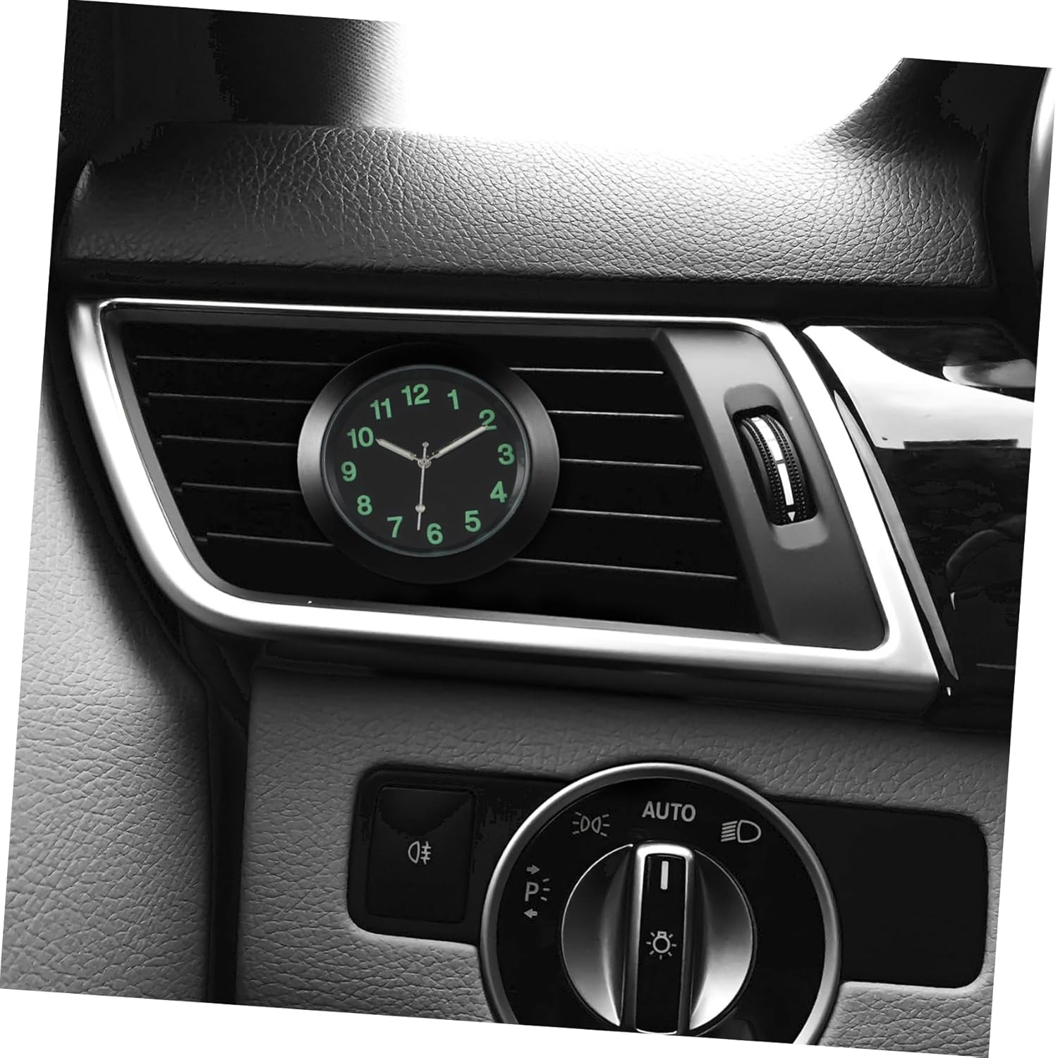 Eine kleine runde Uhr mit grünen Ziffern ist an den Lüftungsschlitzen eines Auto-Armaturenbretts befestigt.