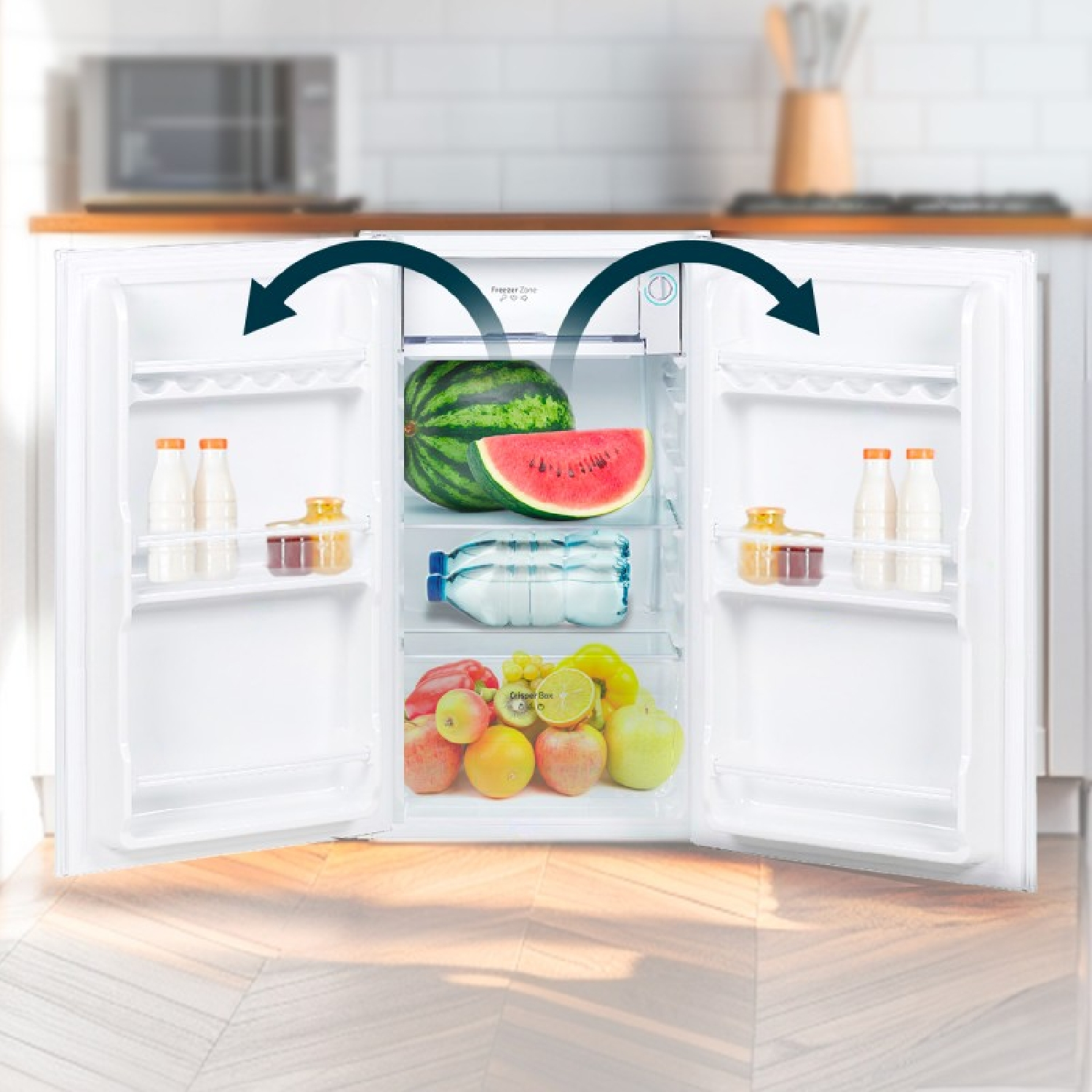 Frigorifero bianco aperto con frutta fresca, cocomero e bottiglie in una cucina luminosa.