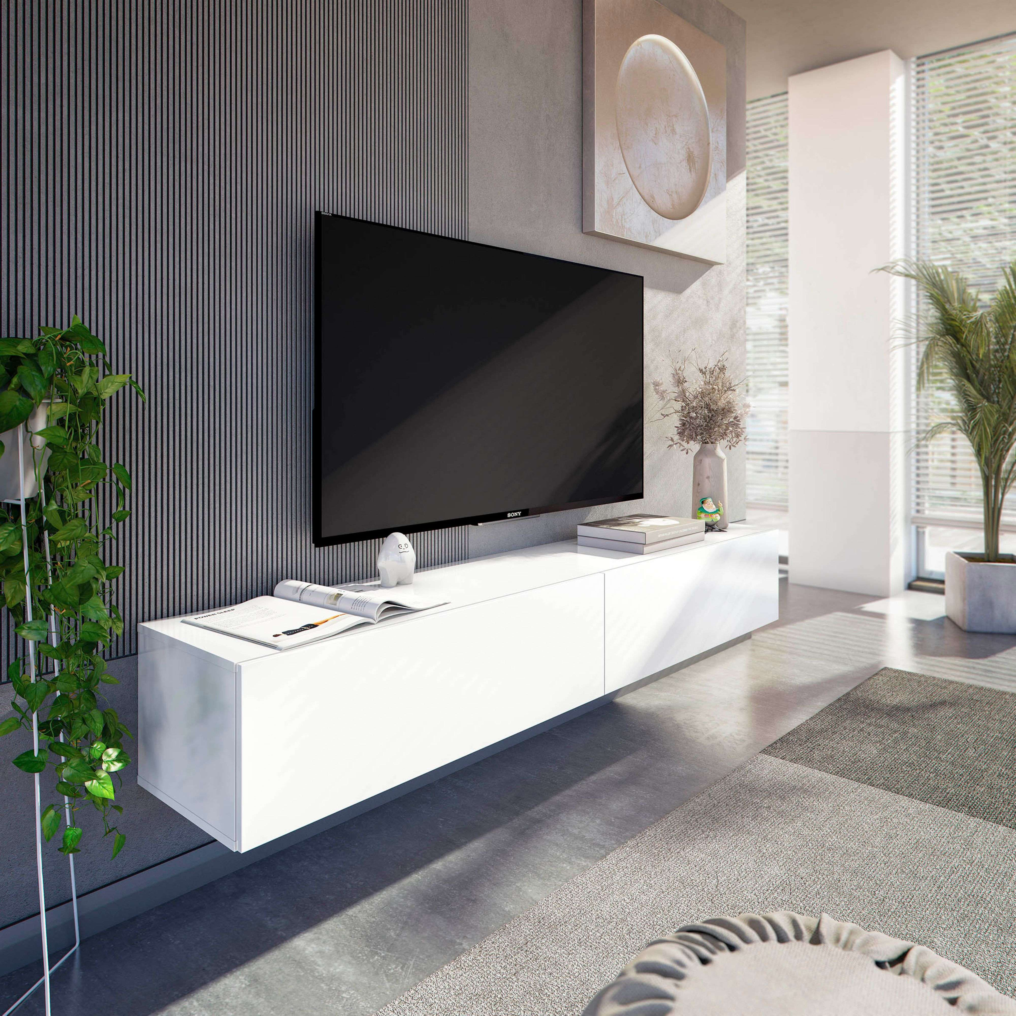 Sala de estar con gran televisor en la pared, mueble blanco flotante, revista abierta y plantas verdes.