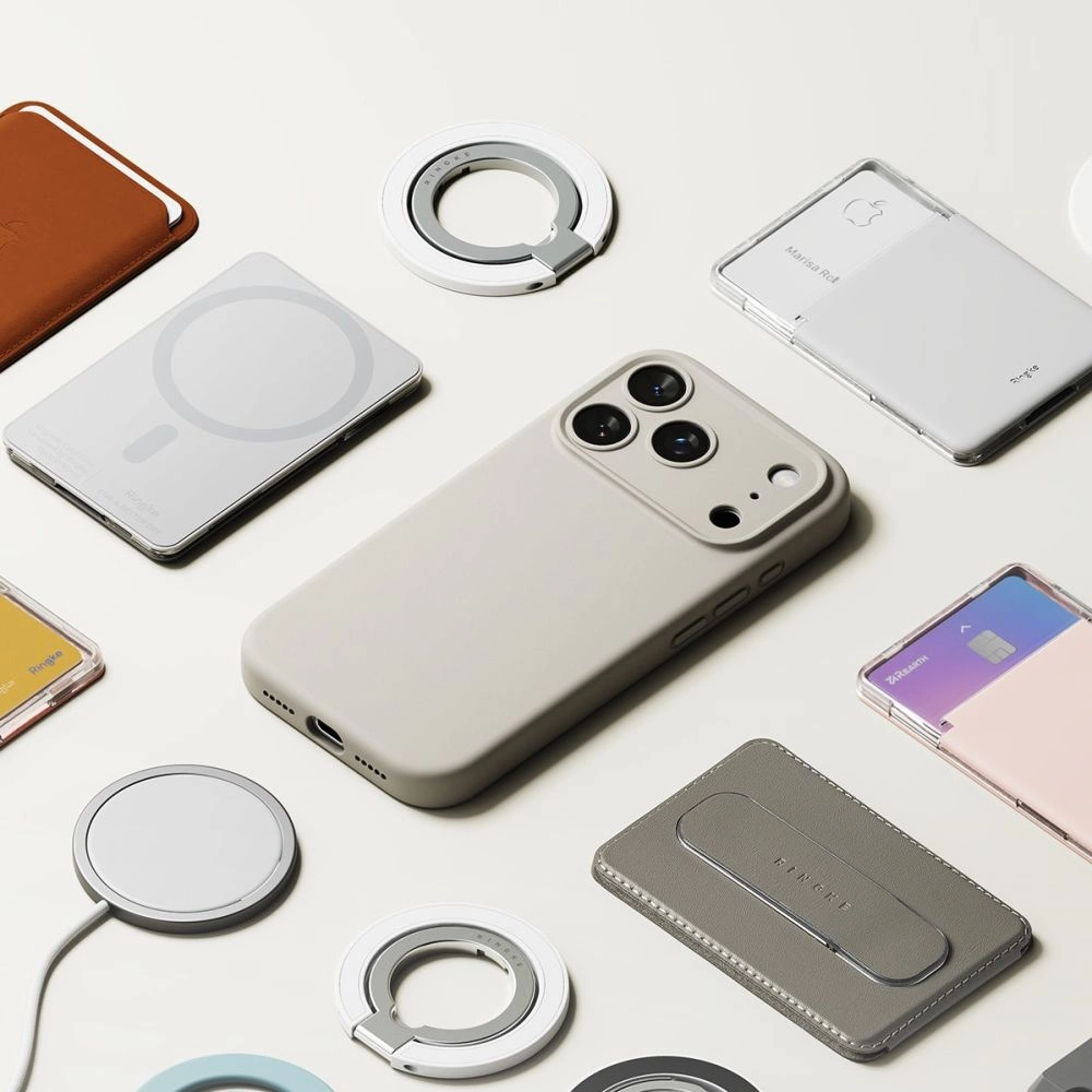 Ein beigees Smartphone in Hülle umgeben von MagSafe-Ladegeräten und Leder-Wallets auf weißem Grund.