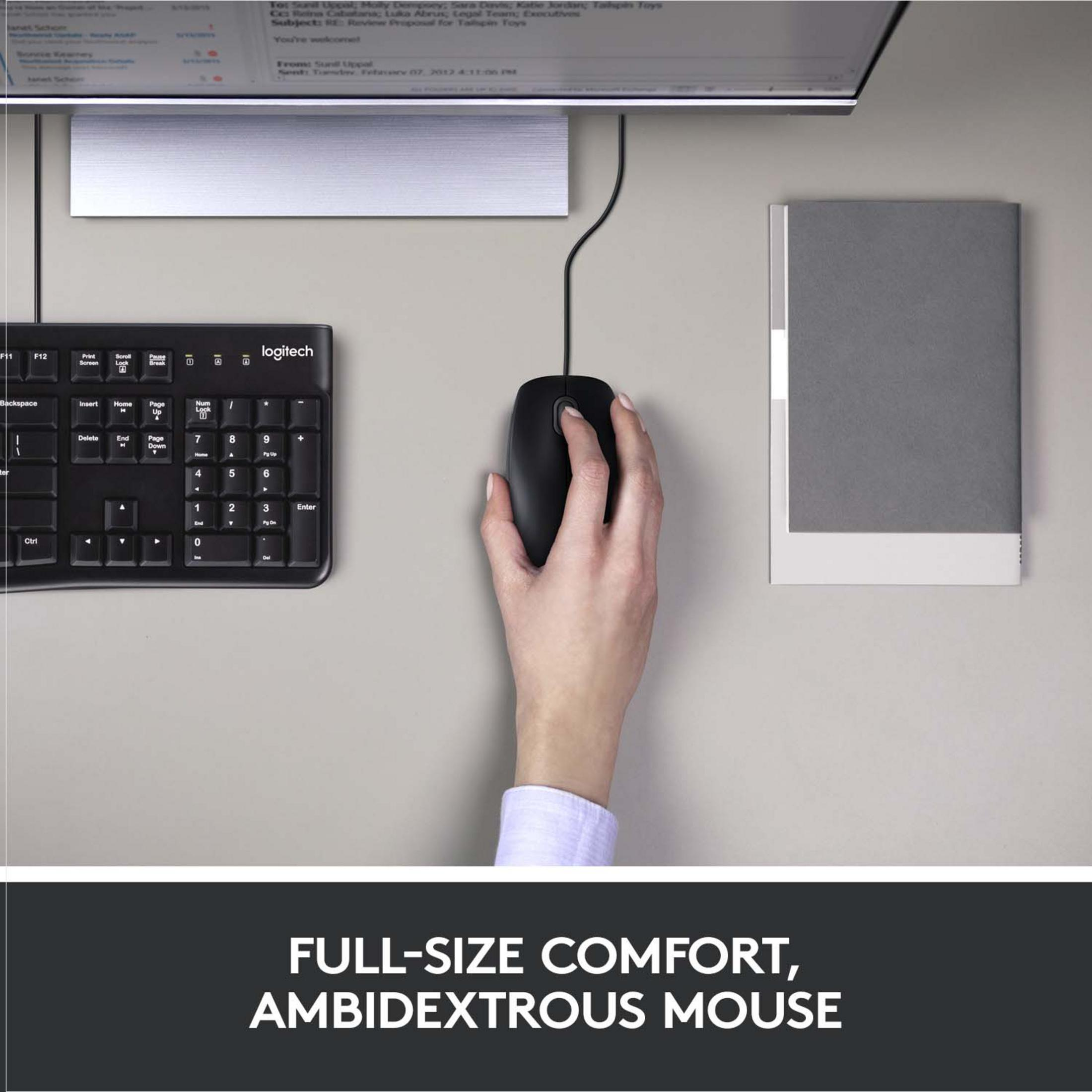 Mano che usa un mouse per computer nero su una scrivania accanto a una tastiera e un taccuino.