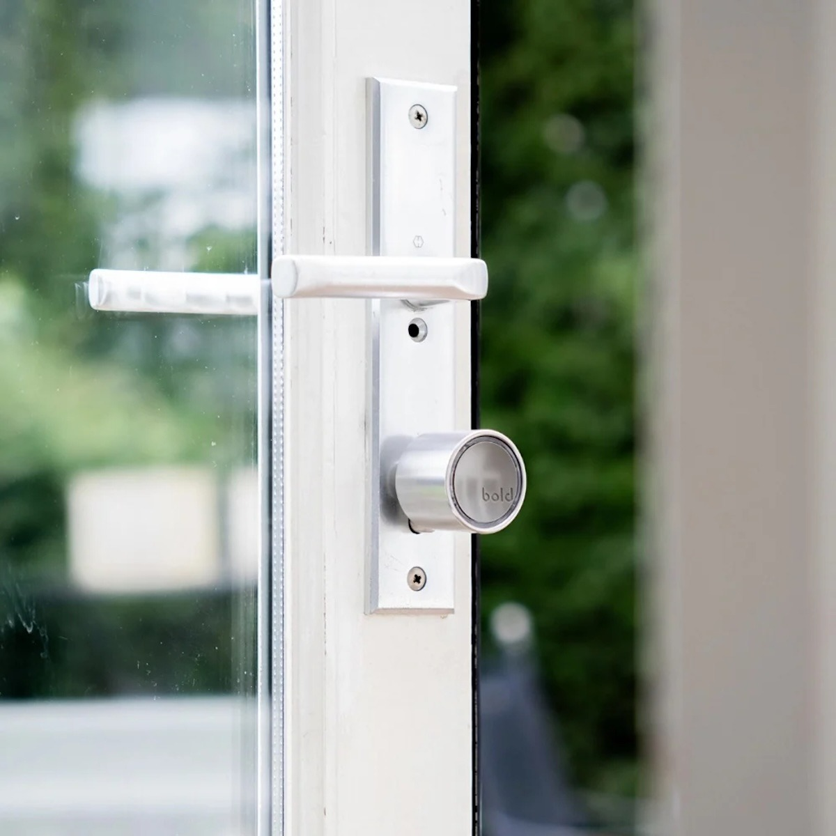 Moderno tirador y cerradura de puerta plateados en una puerta blanca con vidrio.