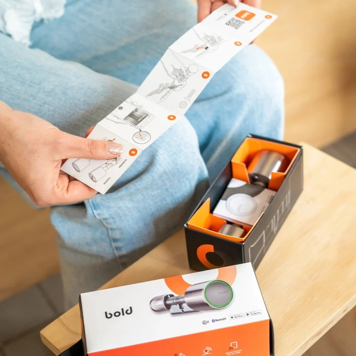 Una persona sostiene un manual de instrucciones junto a una caja de producto abierta.
