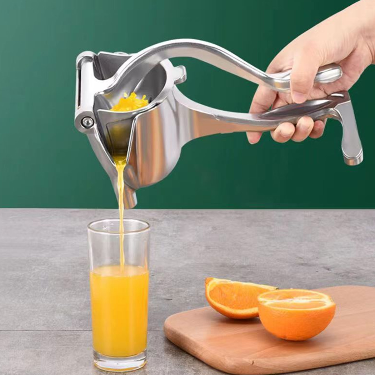 Eine Handpresse presst Orangenextrakt in ein Glas, während Hälften auf einem Holzbrett liegen.