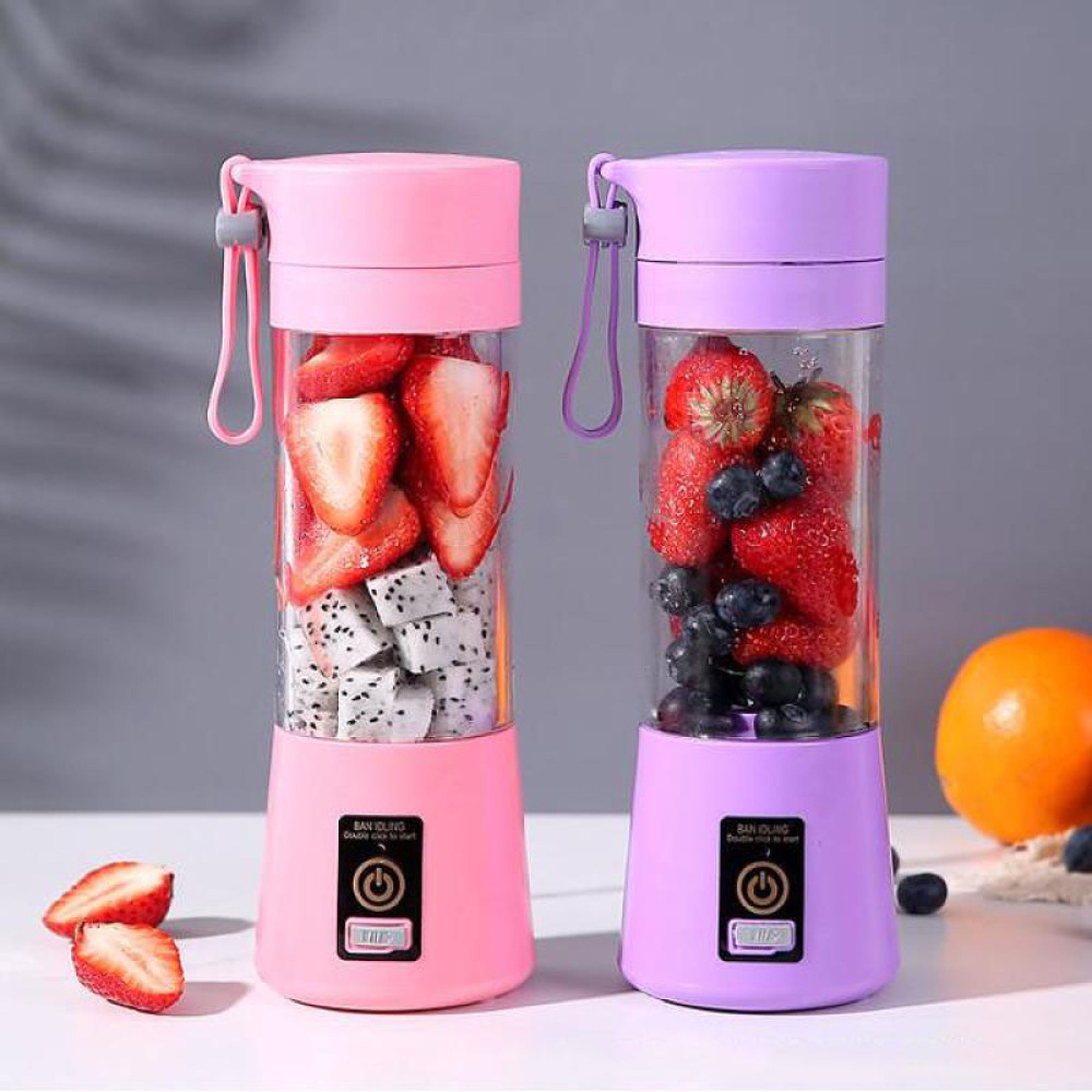 Zwei tragbare Mixer auf einem Tisch mit Erdbeeren, Drachenfrucht und Blaubeeren gefüllt.