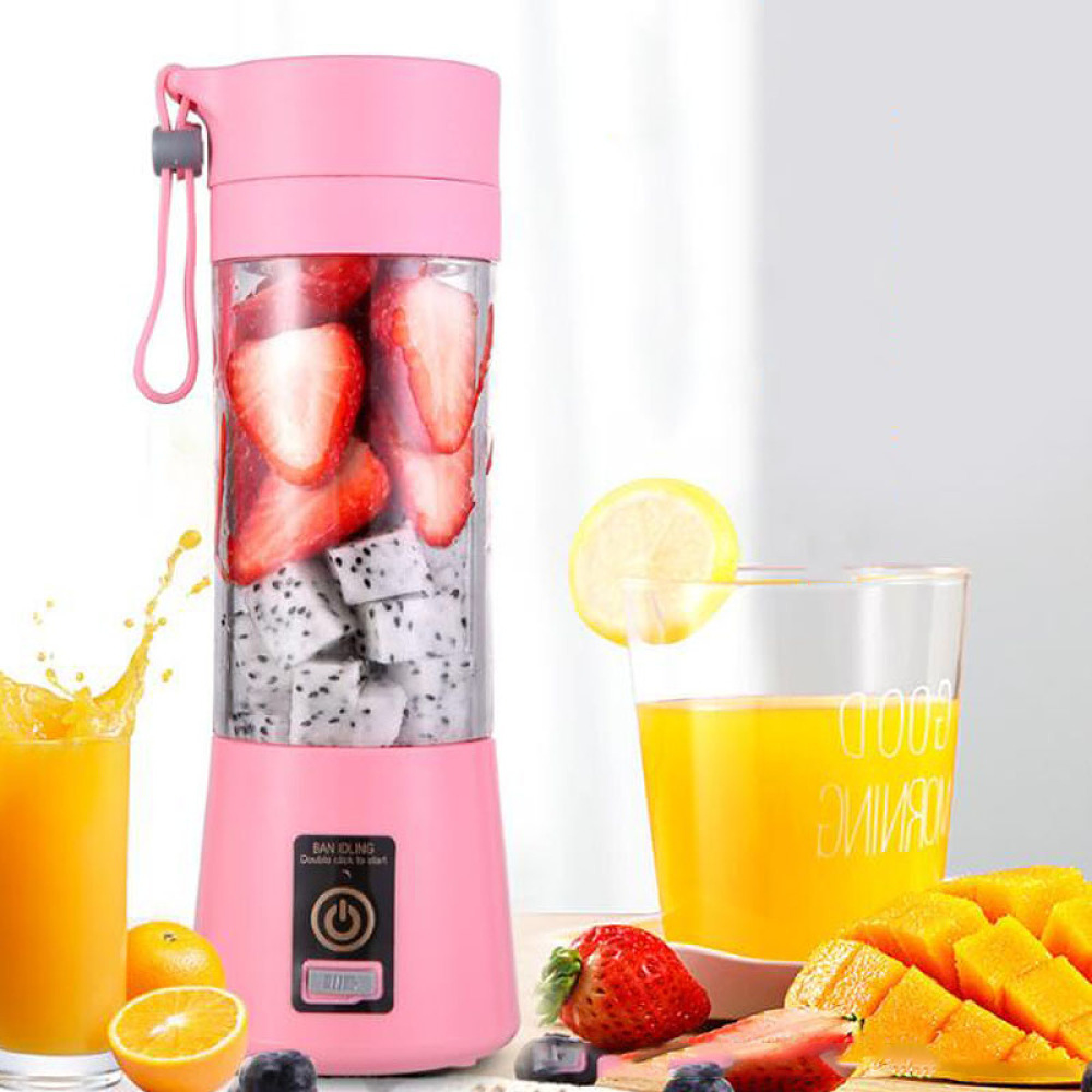 Ein rosa tragbarer Mixer mit Erdbeeren und Drachenfrucht steht neben Gläsern mit Saft und frischem Obst.