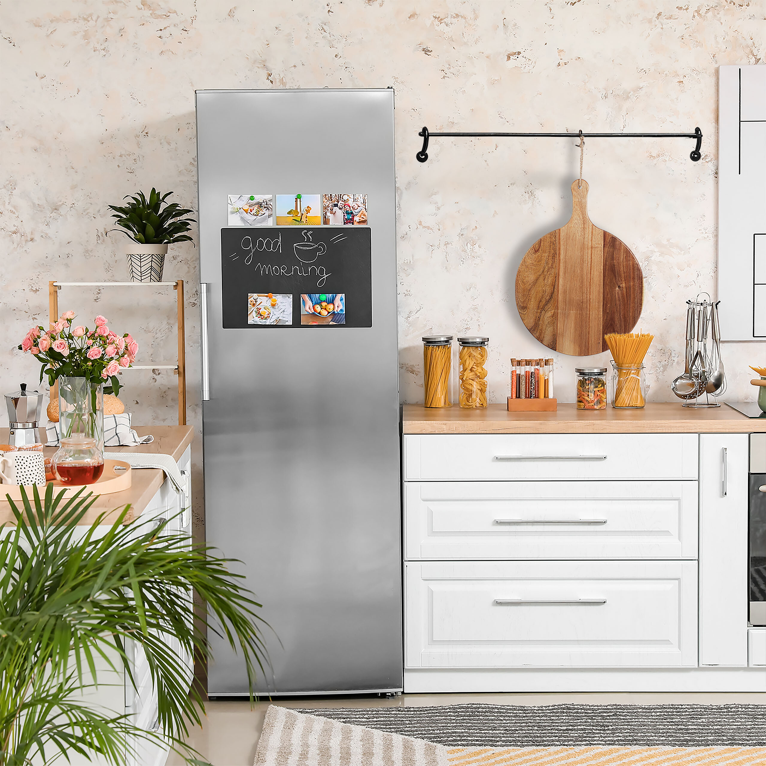 Eine moderne Küche mit einem silbernen Kühlschrank, weißen Schränken, Holzarbeitsplatten und einem Schneidebrett.