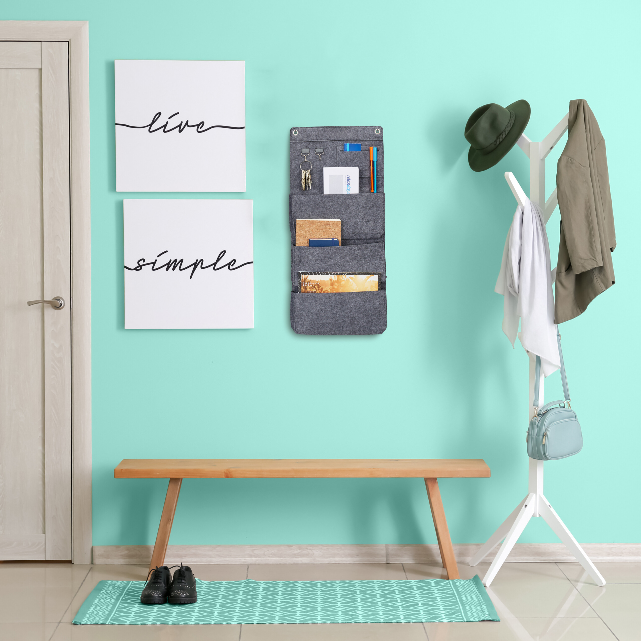 Flur mit mintgrüner Wand, Holzsitzbank, grauem Wandorganizer, weißem Kleiderständer und Schuhen auf dem Teppich.