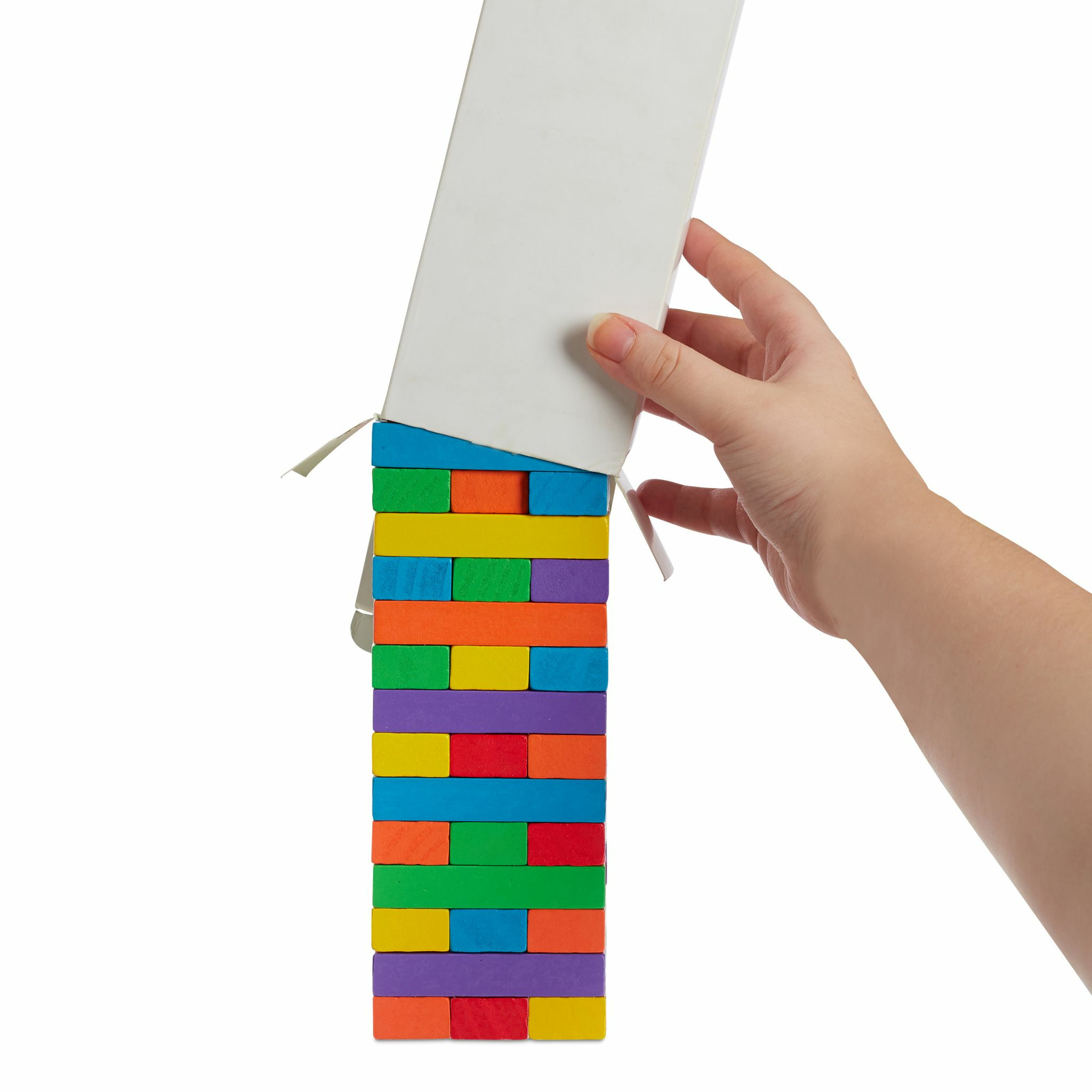 Eine Hand zieht eine weiße Schachtel hoch und enthüllt einen Turm aus bunten Holzblöcken auf weißem Hintergrund.