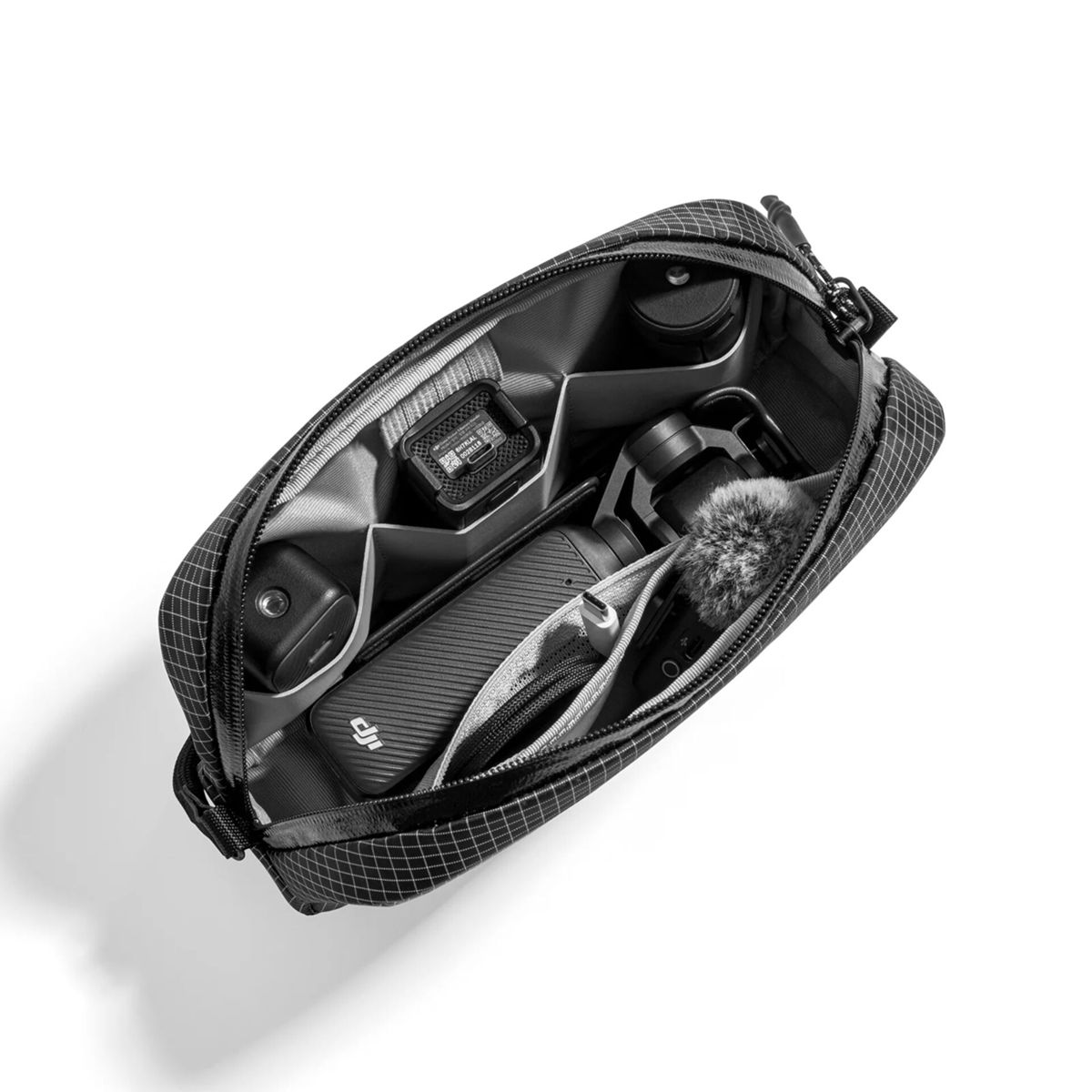 Eine offene schwarze Netztasche mit organisierten Fächern, in denen elektronisches Zubehör und eine Kamera liegen.