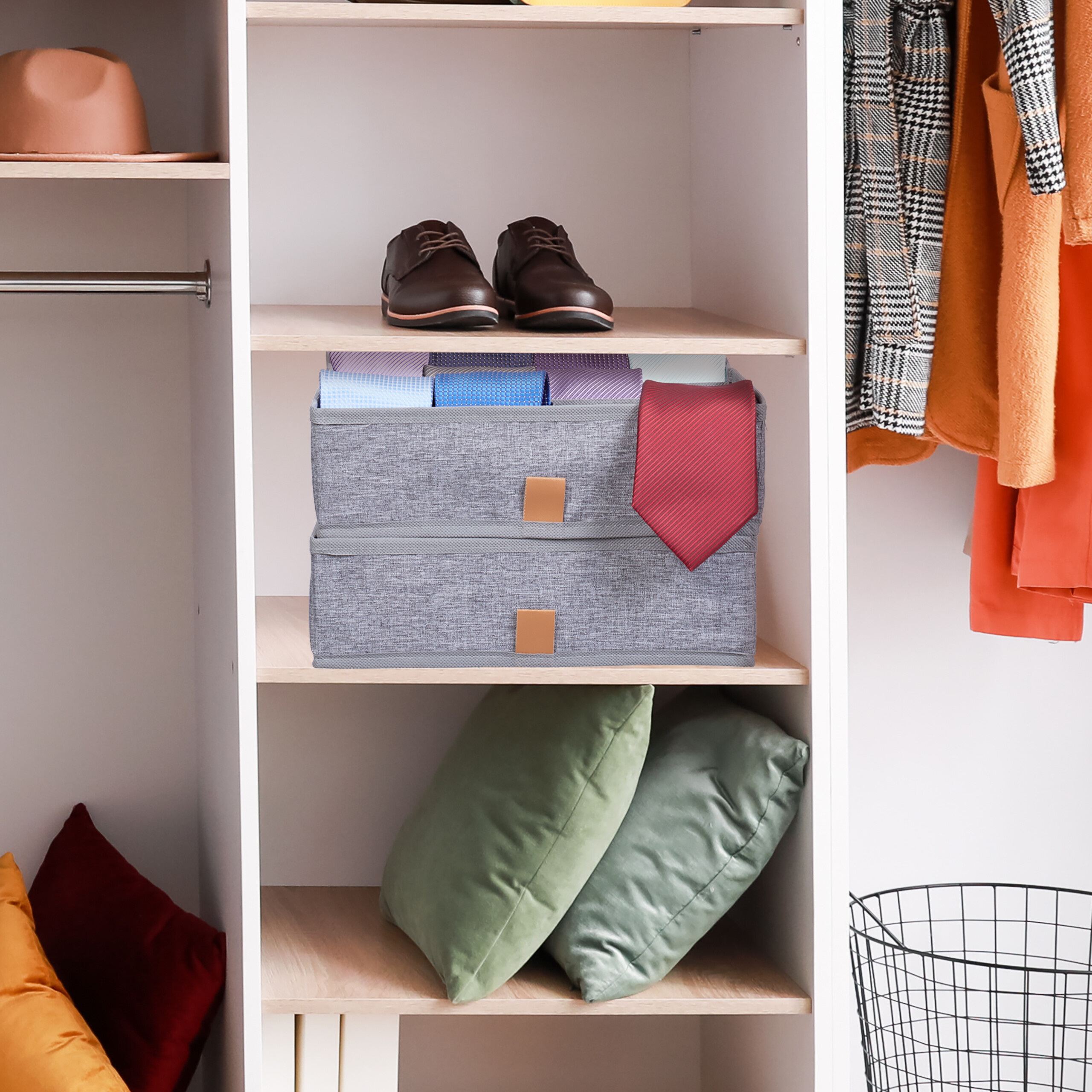 Organisierter weißer Schrank mit braunen Schuhen, grauen Aufbewahrungsboxen mit Krawatten und zwei grünen Kissen.