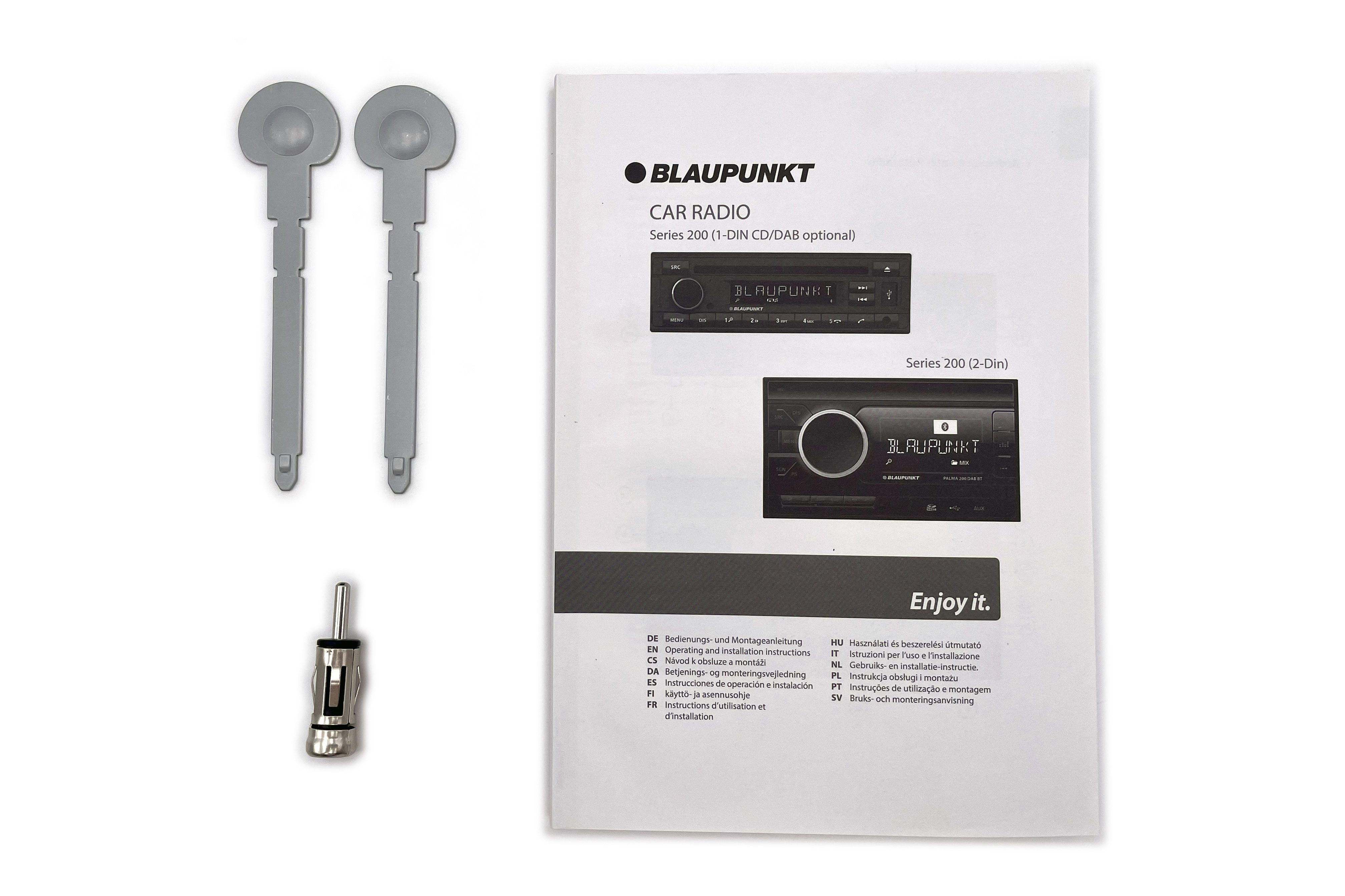 Ein Blaupunkt-Autoradio-Handbuch liegt neben zwei grauen Ausbauwerkzeugen und einem Antennenadapter.
