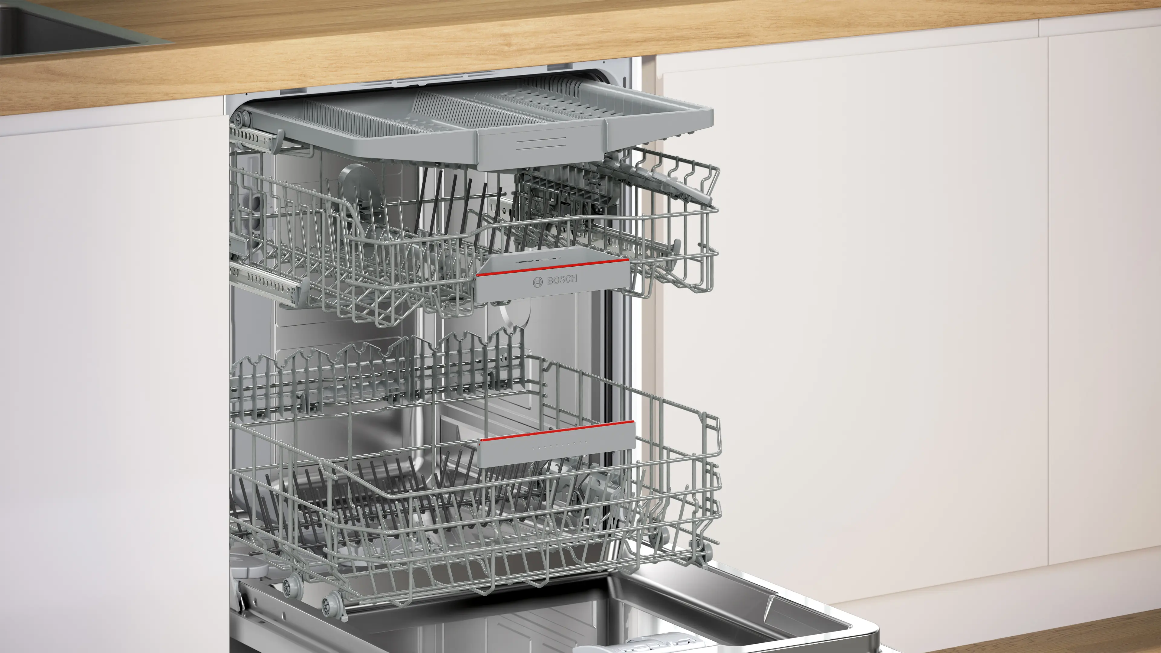 Una lavastoviglie aperta con tre cestelli grigi estraibili in una cucina moderna.