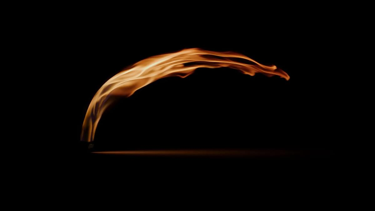 Eine bogenförmige Flamme brennt gegen einen schwarzen Hintergrund und erzeugt ein warmes Leuchten.
