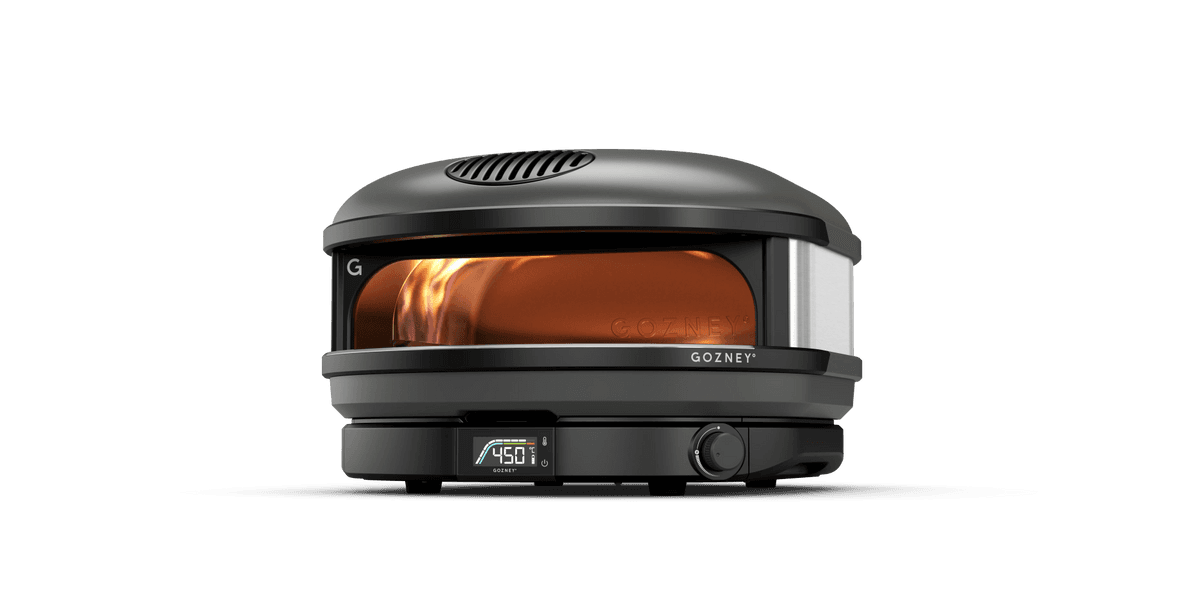 Ein kompakter, schwarzer Gozney Pizzaofen mit leuchtenden Flammen im Inneren und einem digitalen Display bei 450 Grad.