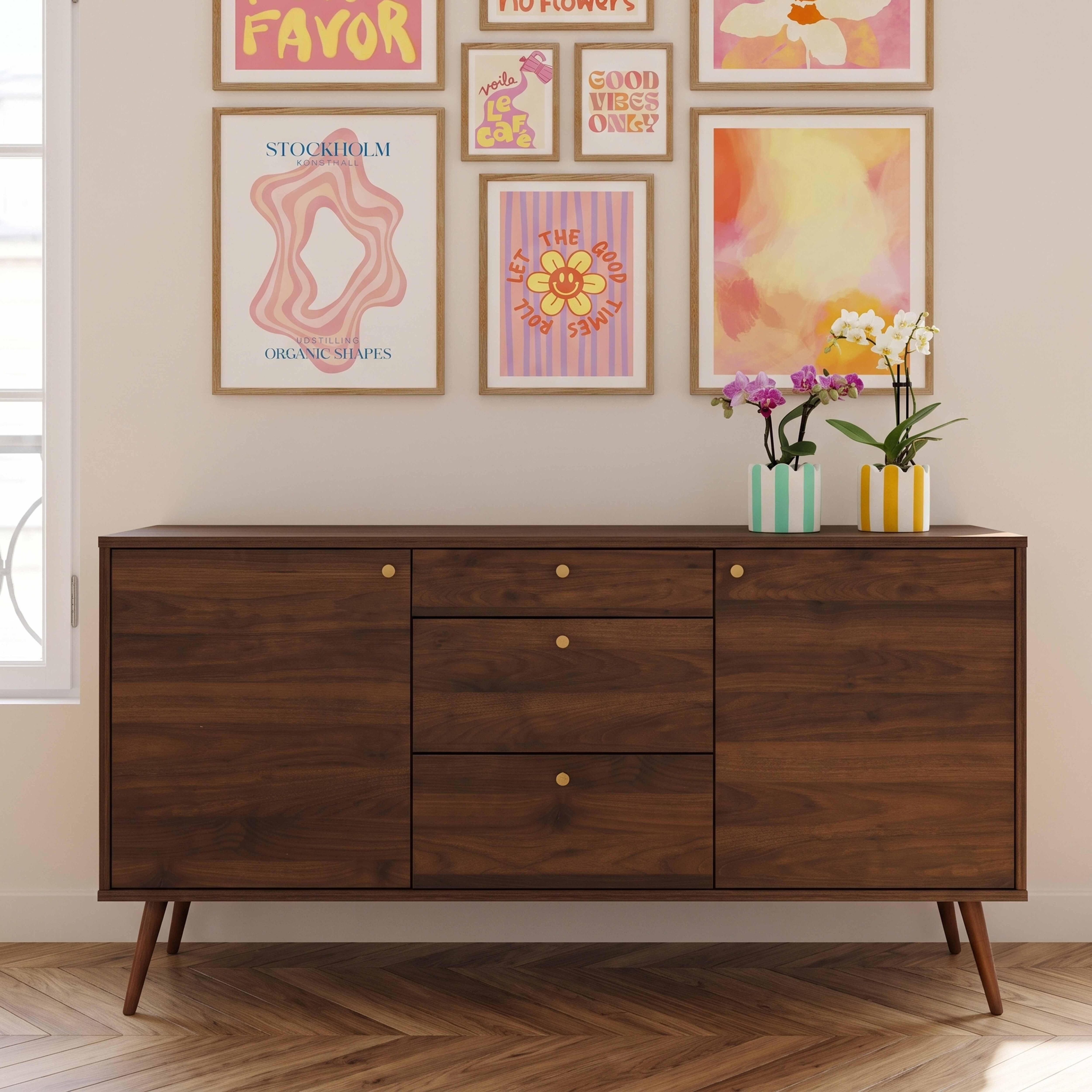 Ein dunkles Holzsideboard mit bunten Postern und Orchideen im Topf an der Wand.