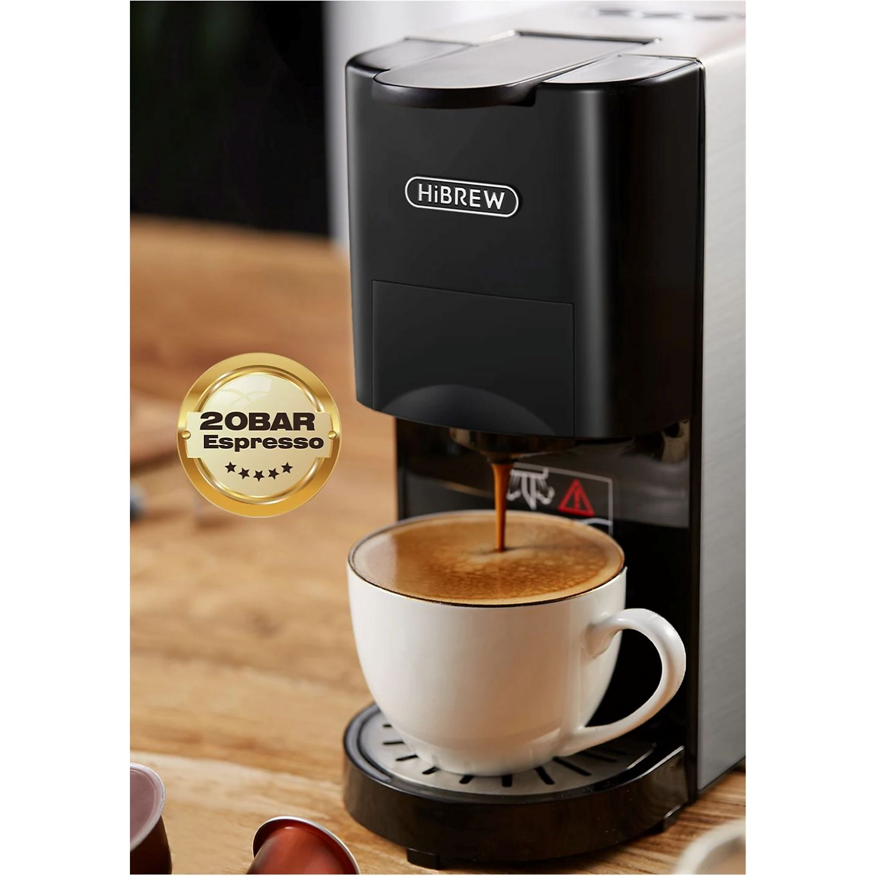 Eine schwarze HiBrew Kaffeemaschine brüht Espresso in eine weiße Tasse auf einem Holztisch.