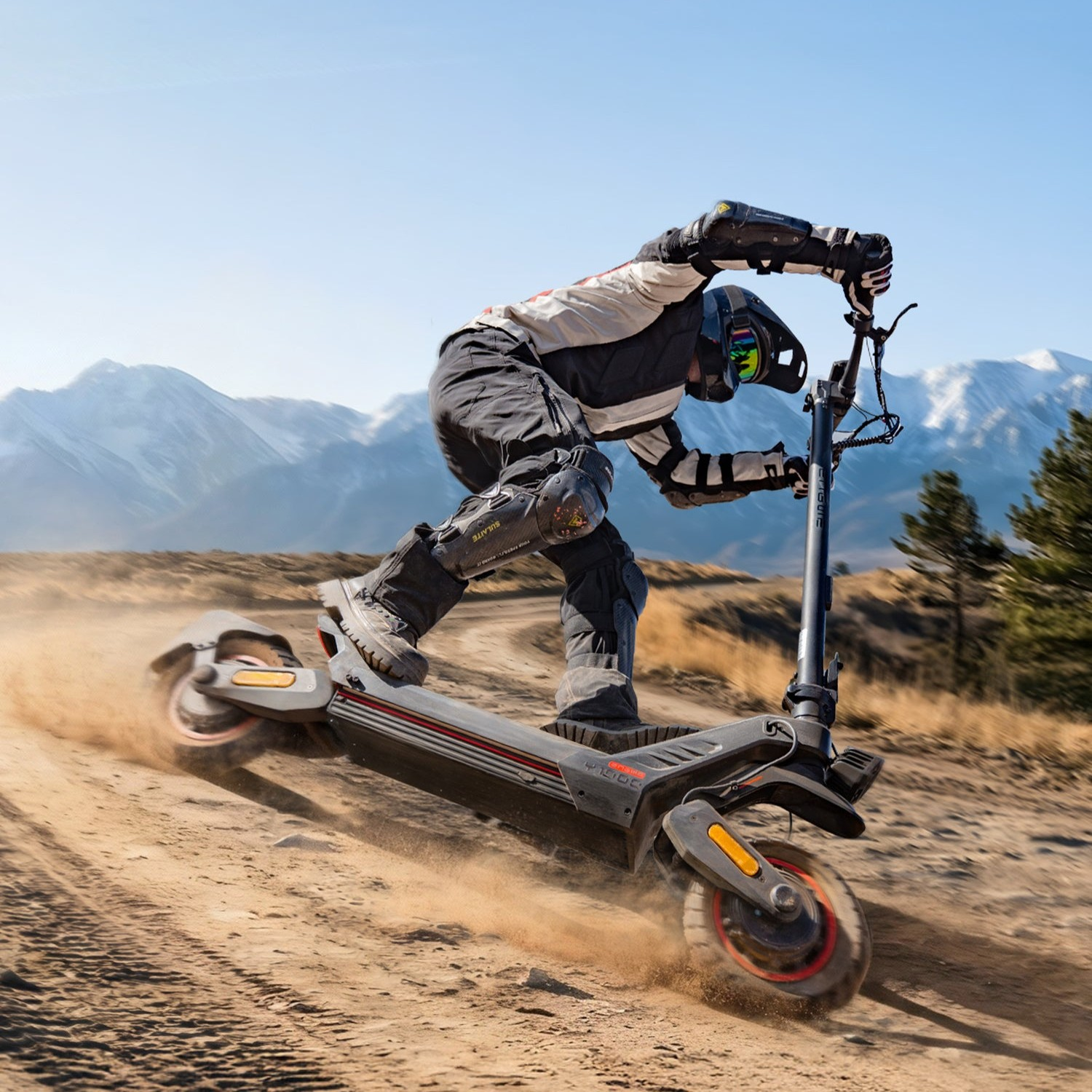 Una persona con equipo de protección conduce un patinete eléctrico rápidamente por un camino de tierra.