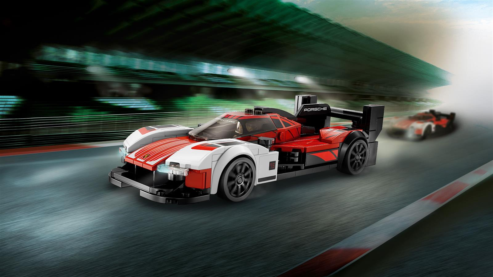 Ein roter und weißer Lego-Porsche-Rennwagen rast auf einer Rennstrecke vor einer unscharfen Tribüne.