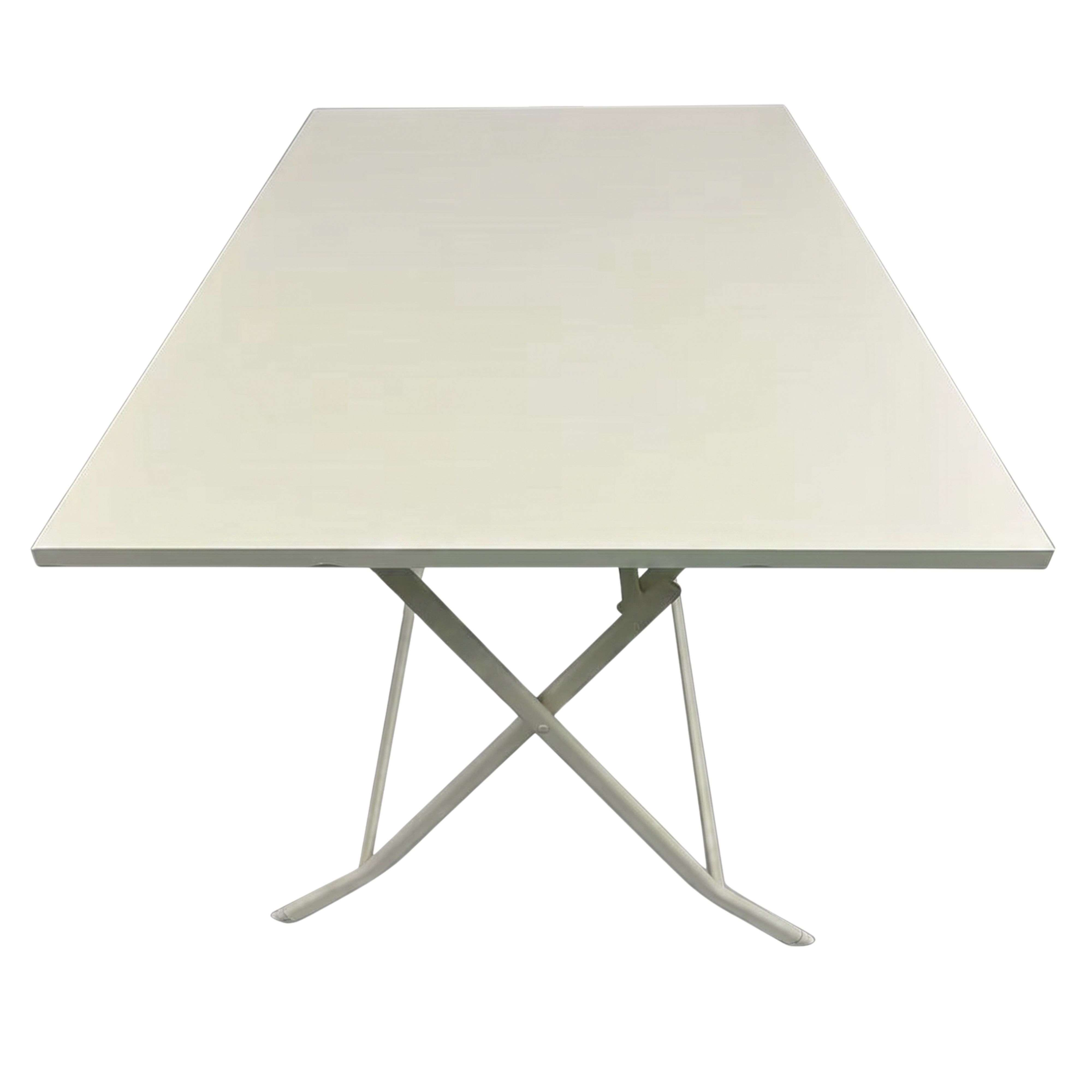 Una mesa plegable rectangular blanca con patas de metal en forma de X sobre fondo blanco.