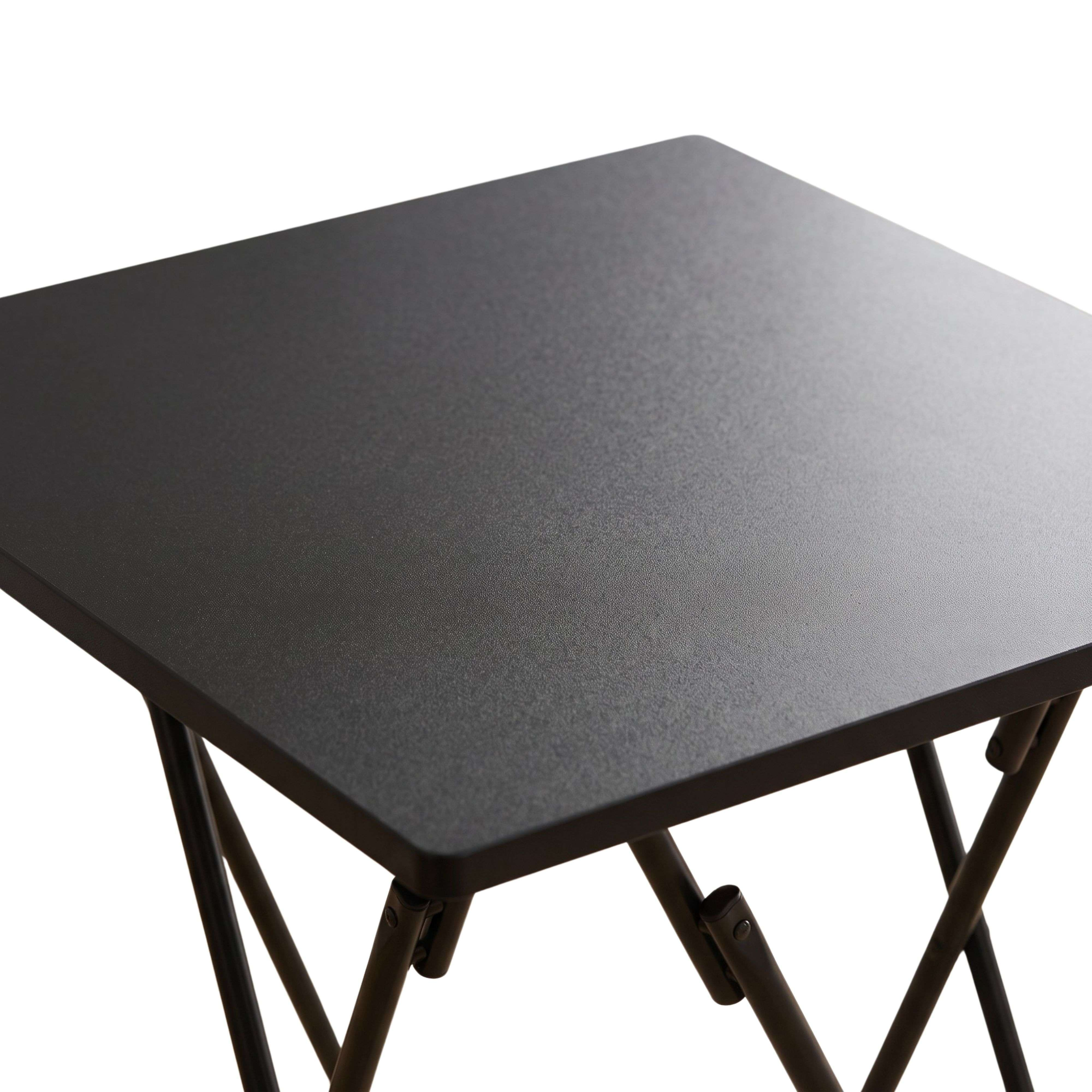 Una pequeña mesa plegable negra con superficie texturizada sobre fondo blanco.