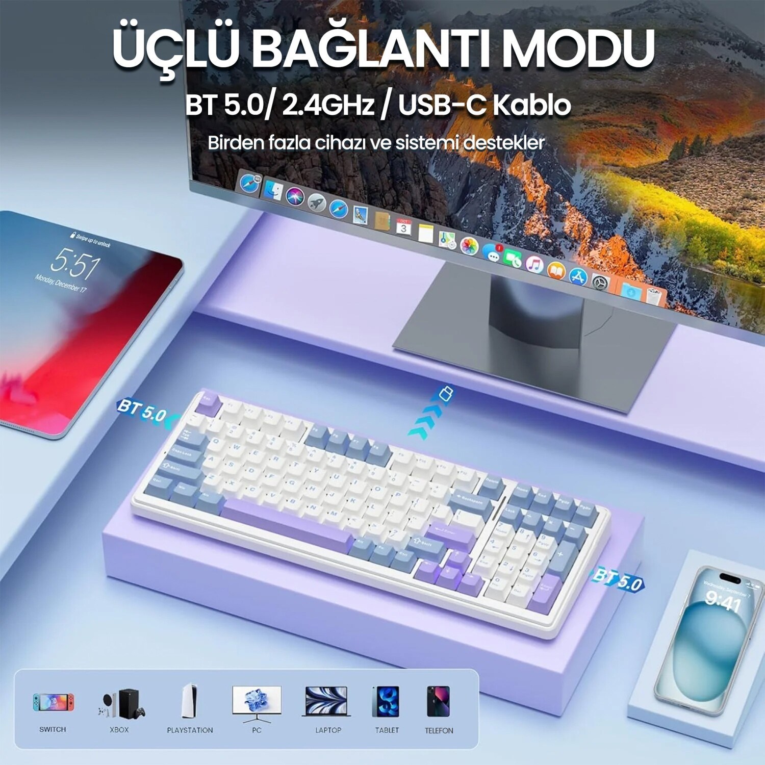 Açık mavi masa üzerinde monitör, tablet ve akıllı telefonun yanında beyaz ve mavi mekanik klavye.