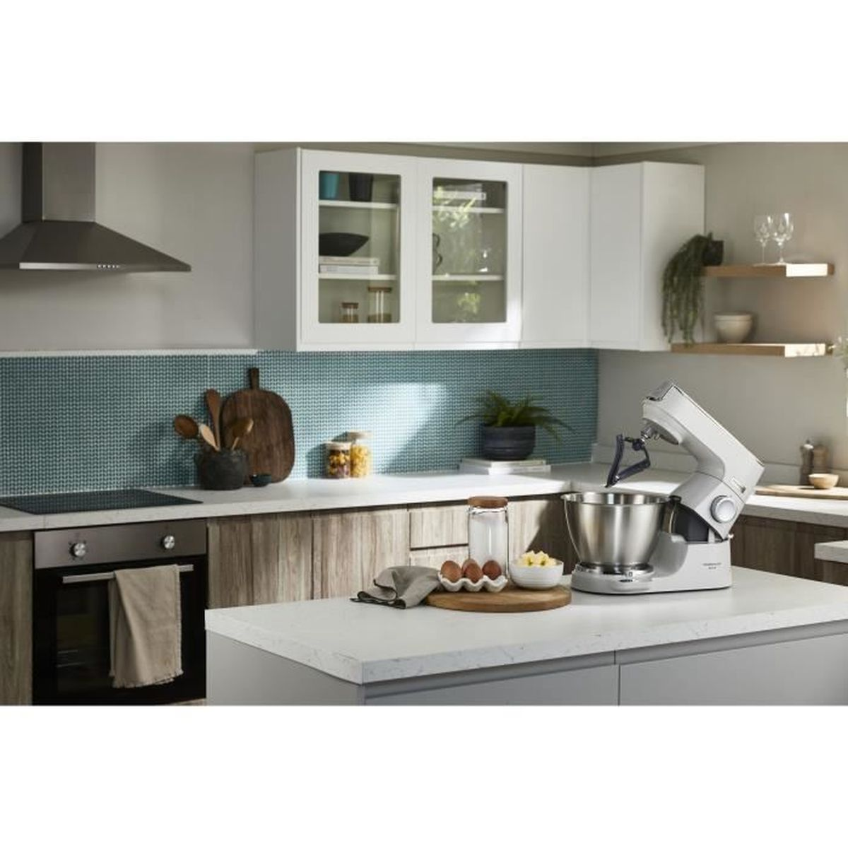 Cocina moderna con batidora blanca, horno, encimera de madera y azulejos de mosaico azul en la pared.