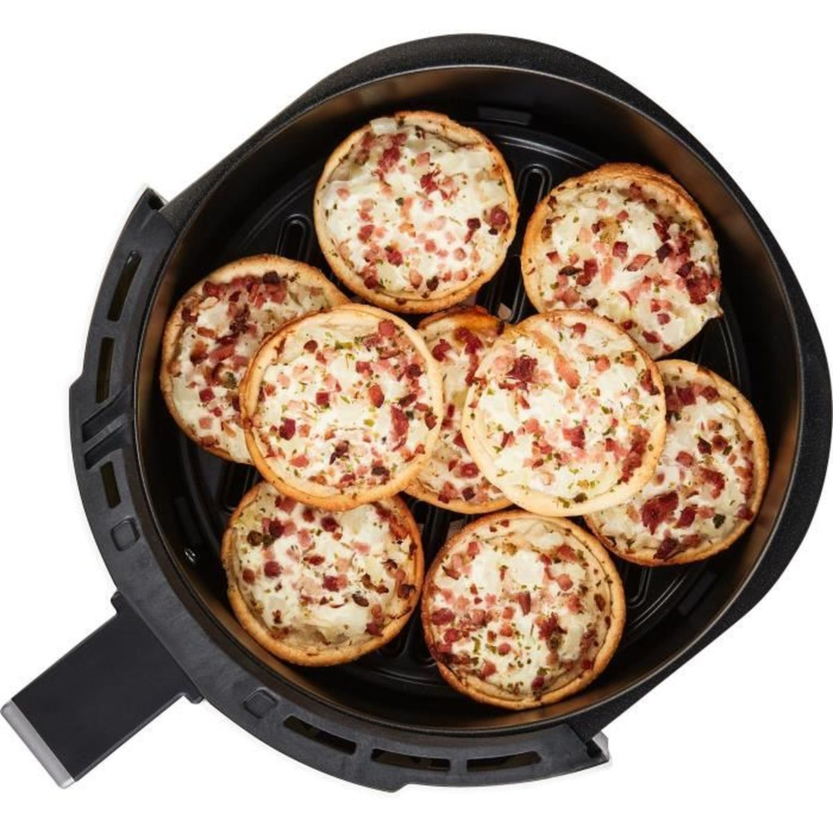 Ansicht von oben auf kleine Quiches mit Speck in einem schwarzen Heißluftfritteusenkorb.