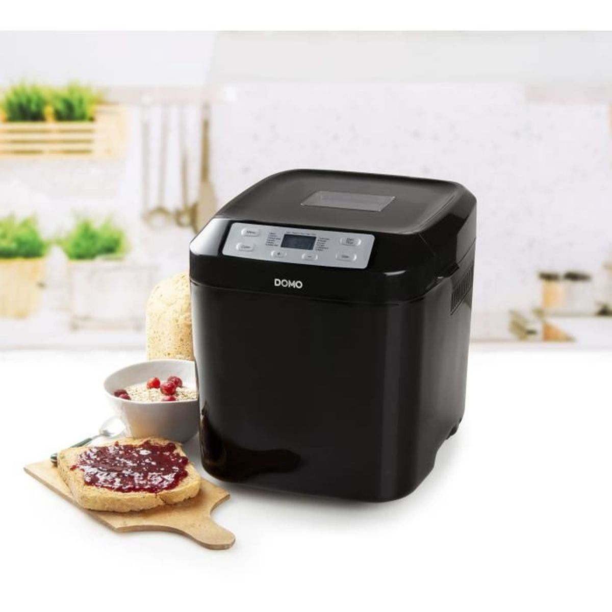 Ein schwarzer Brotbackautomat steht auf einer Küchentheke, neben Toast mit Marmelade und einer Schüssel.