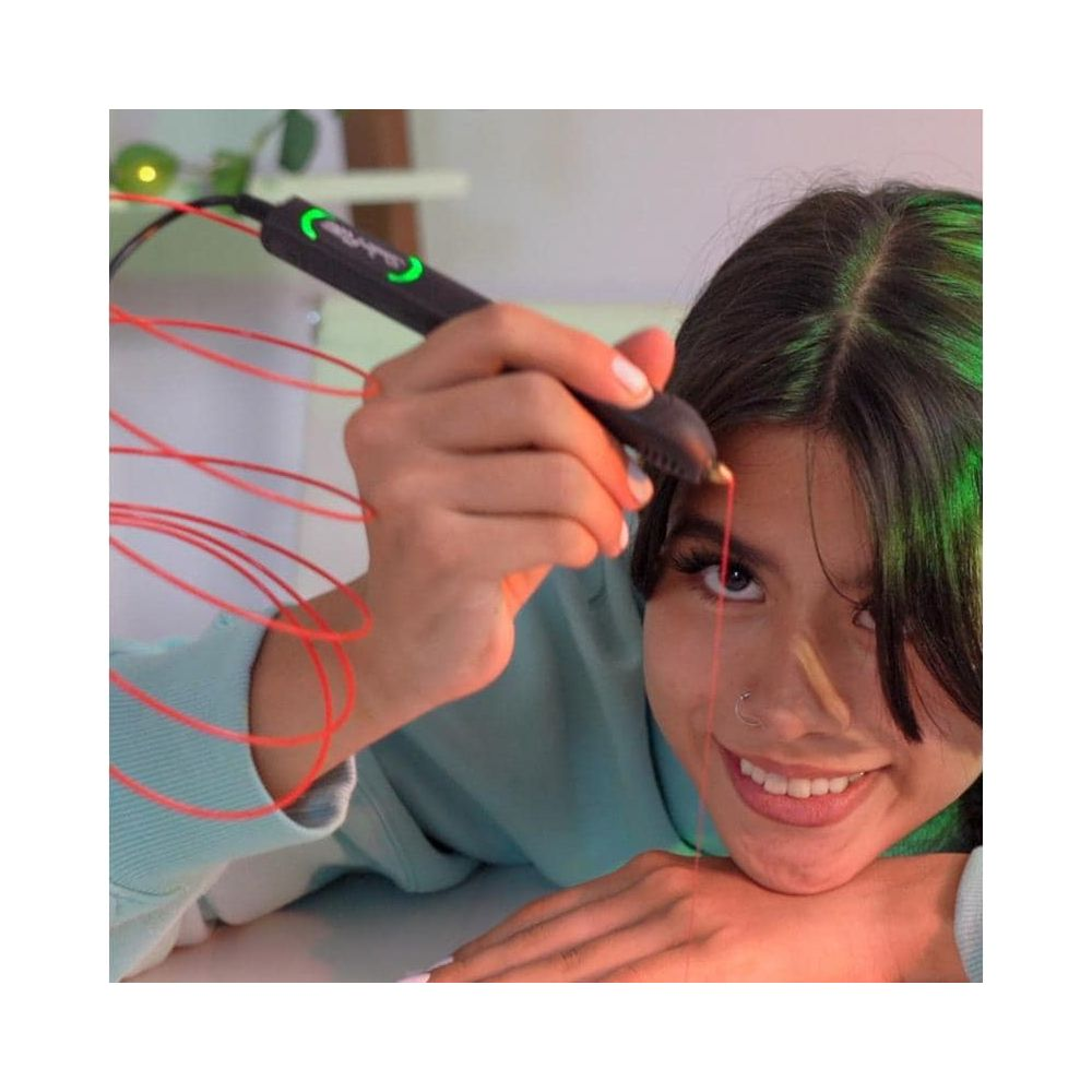 Una ragazza sorridente disegna un filo rosso sul suo viso usando una penna 3D.