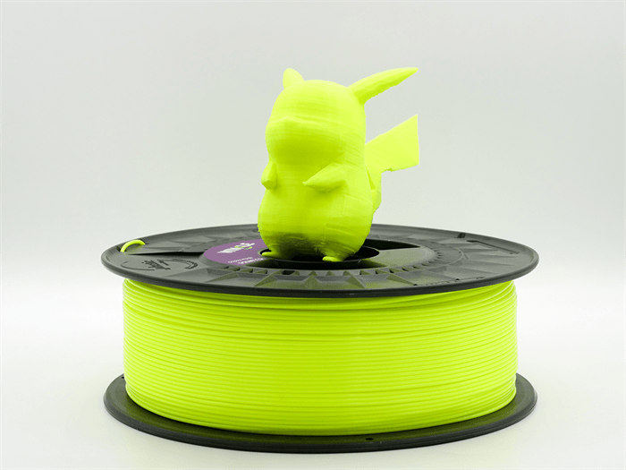 Una statuetta di Pikachu stampata in 3D giallo brillante si trova sopra una bobina di filamento gialla.