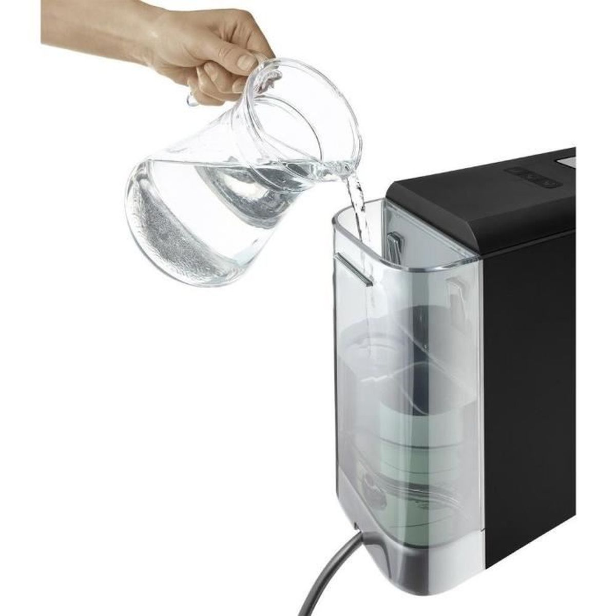 Eine Hand gießt Wasser aus einer Glas-Karaffe in den transparenten Wassertank einer Kaffeemaschine.