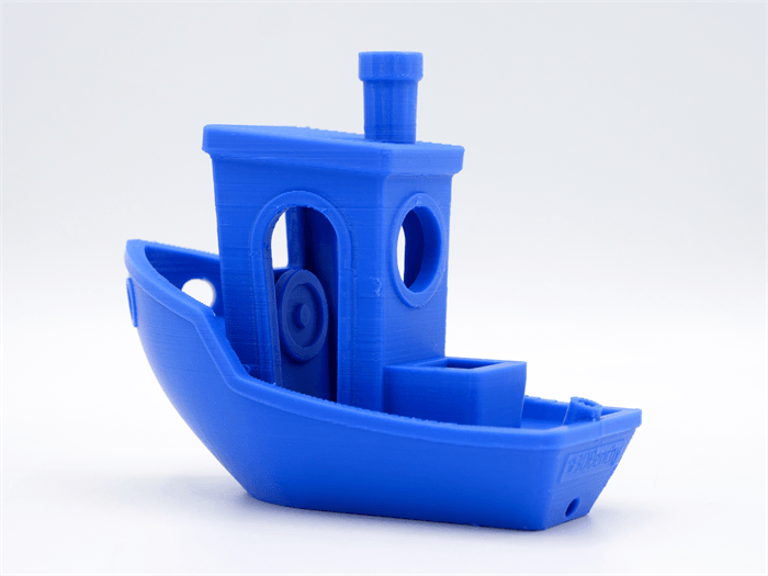 Una barca Benchy stampata in 3D blu su sfondo bianco.