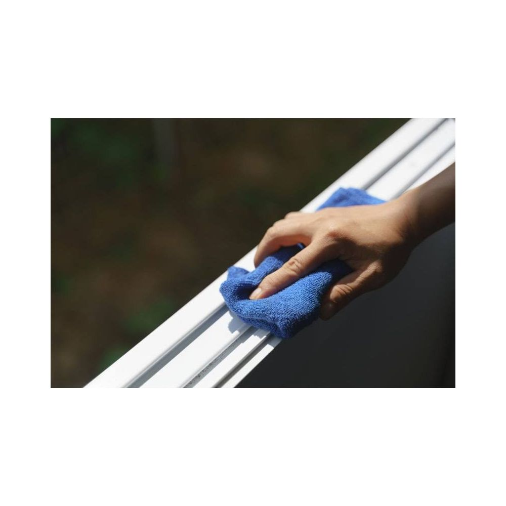 Eine Hand wischt mit einem blauen Tuch einen weißen Fensterrahmen ab.