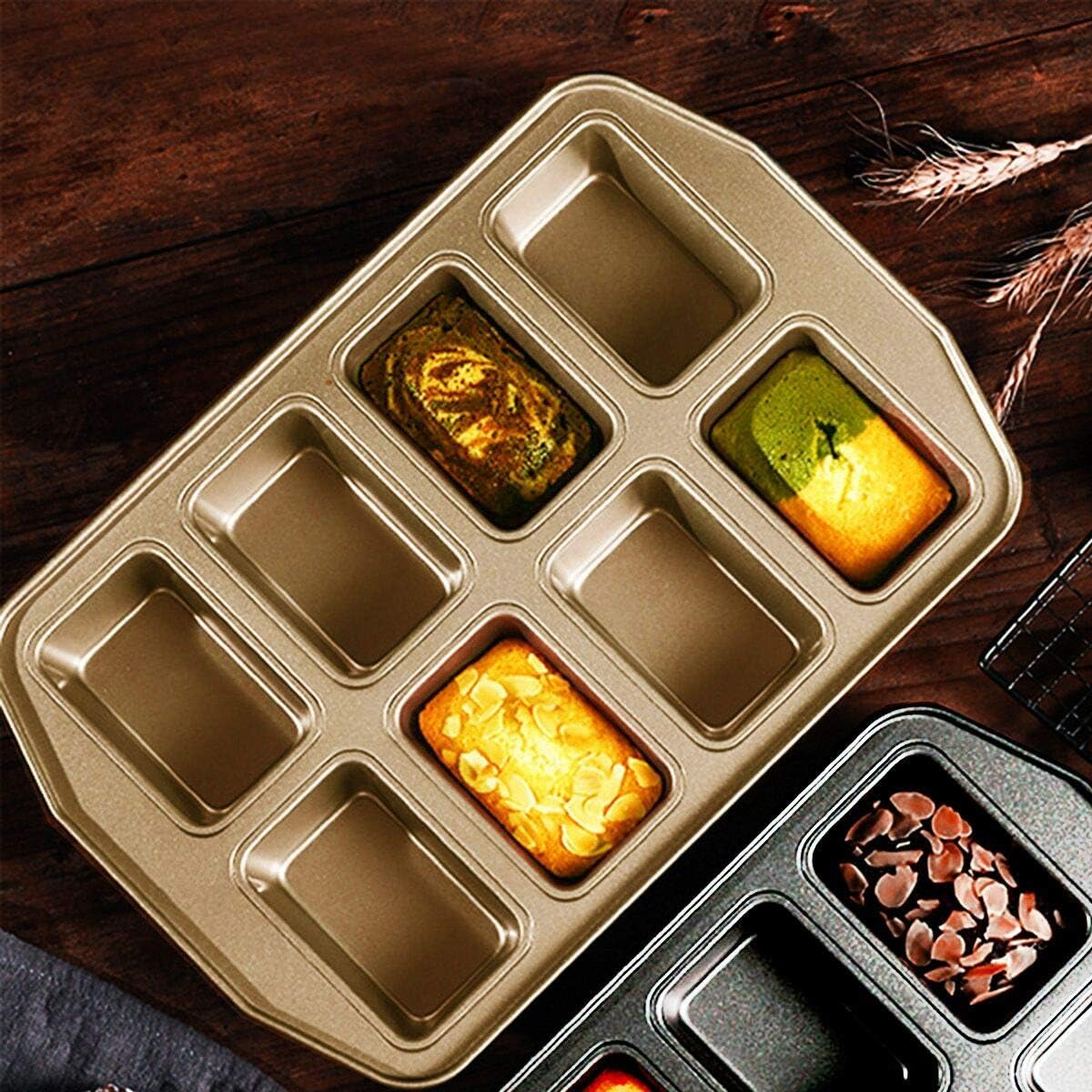 Eine goldfarbene Backform für mehrere kleine Brote liegt auf einem dunklen Holztisch.