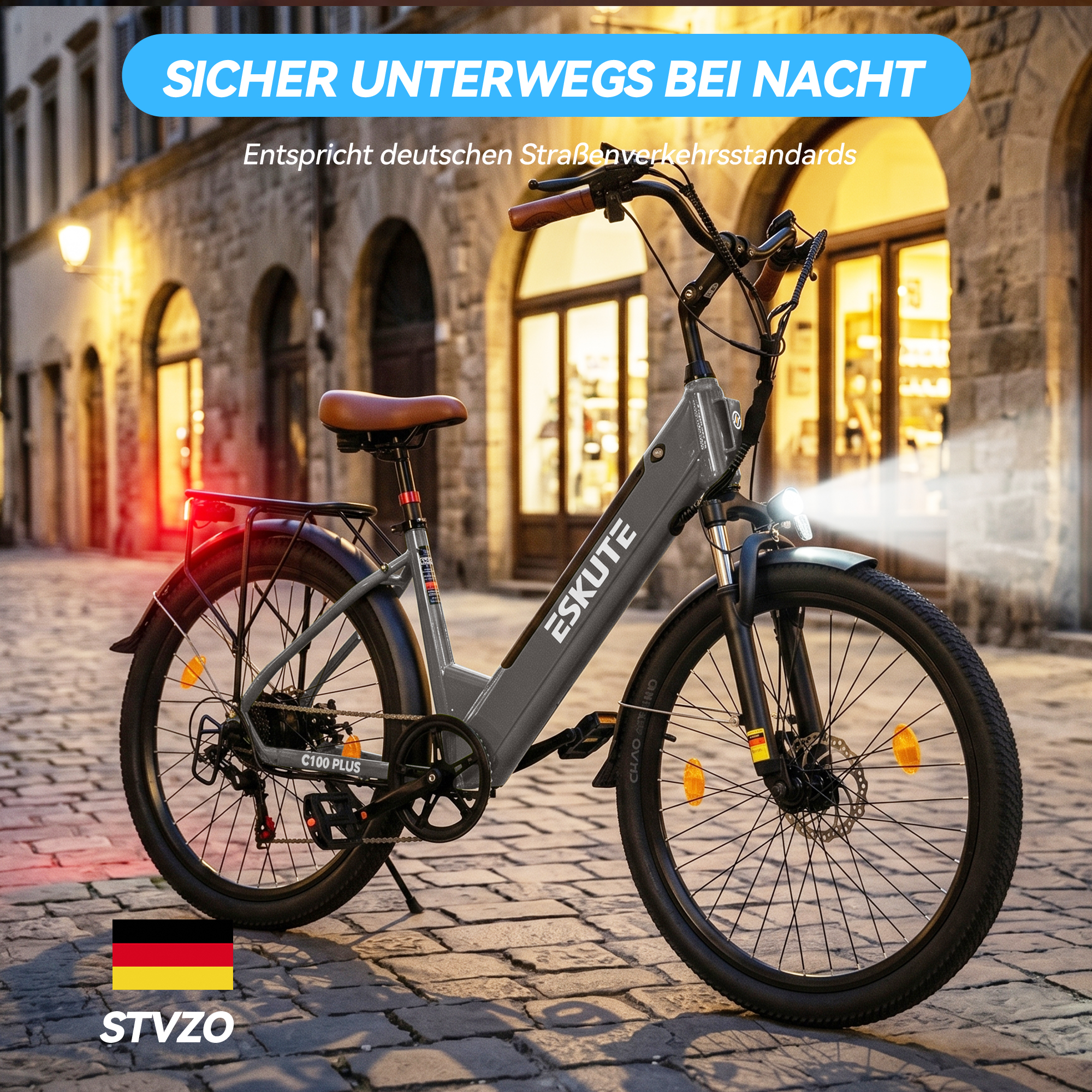 Ein graues Eskute E-Bike steht auf nächtlichem Kopfsteinpflaster mit eingeschaltetem Licht.