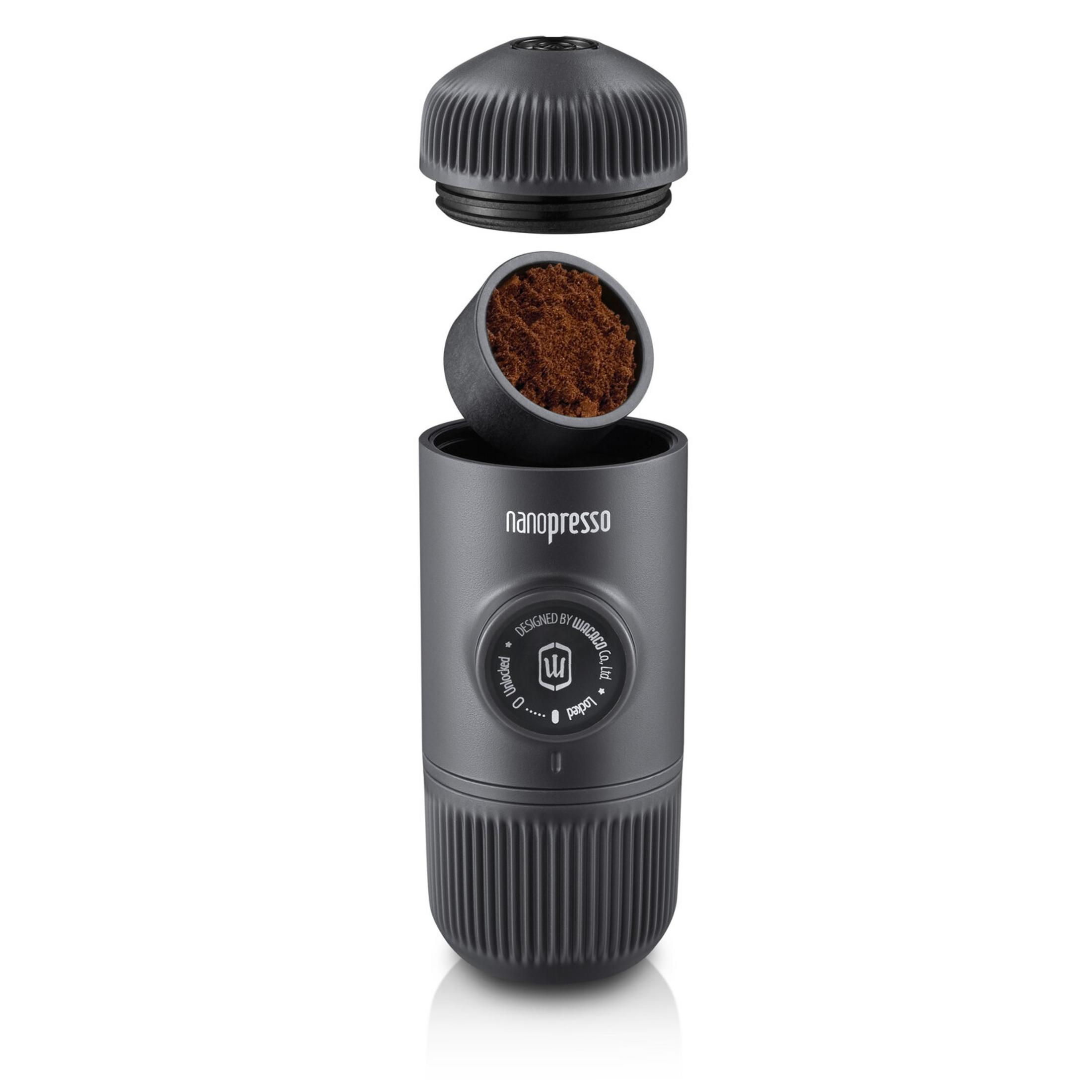 Una caffettiera Nanopresso nera con caffè macinato, capsula e tappo fluttuanti sopra il corpo.