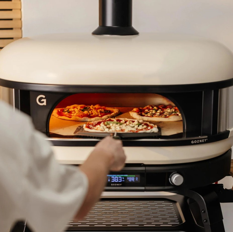 Eine weiße Gozney-Pizzaofen wird in der Küche verwendet, mit Pizzas drinnen.