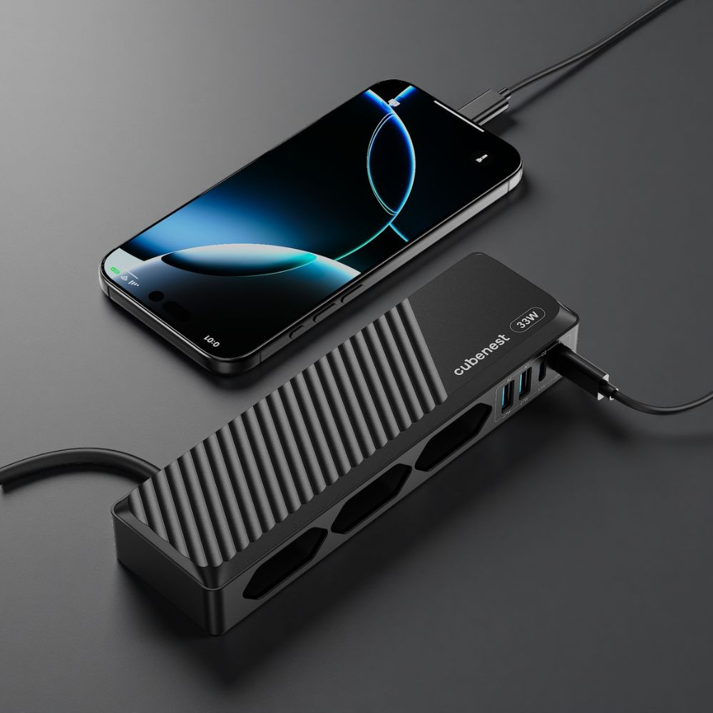 Ein schwarzer Cubenest Mehrfachstecker mit Netzteil und ein Smartphone laden auf einer dunklen Oberfläche.