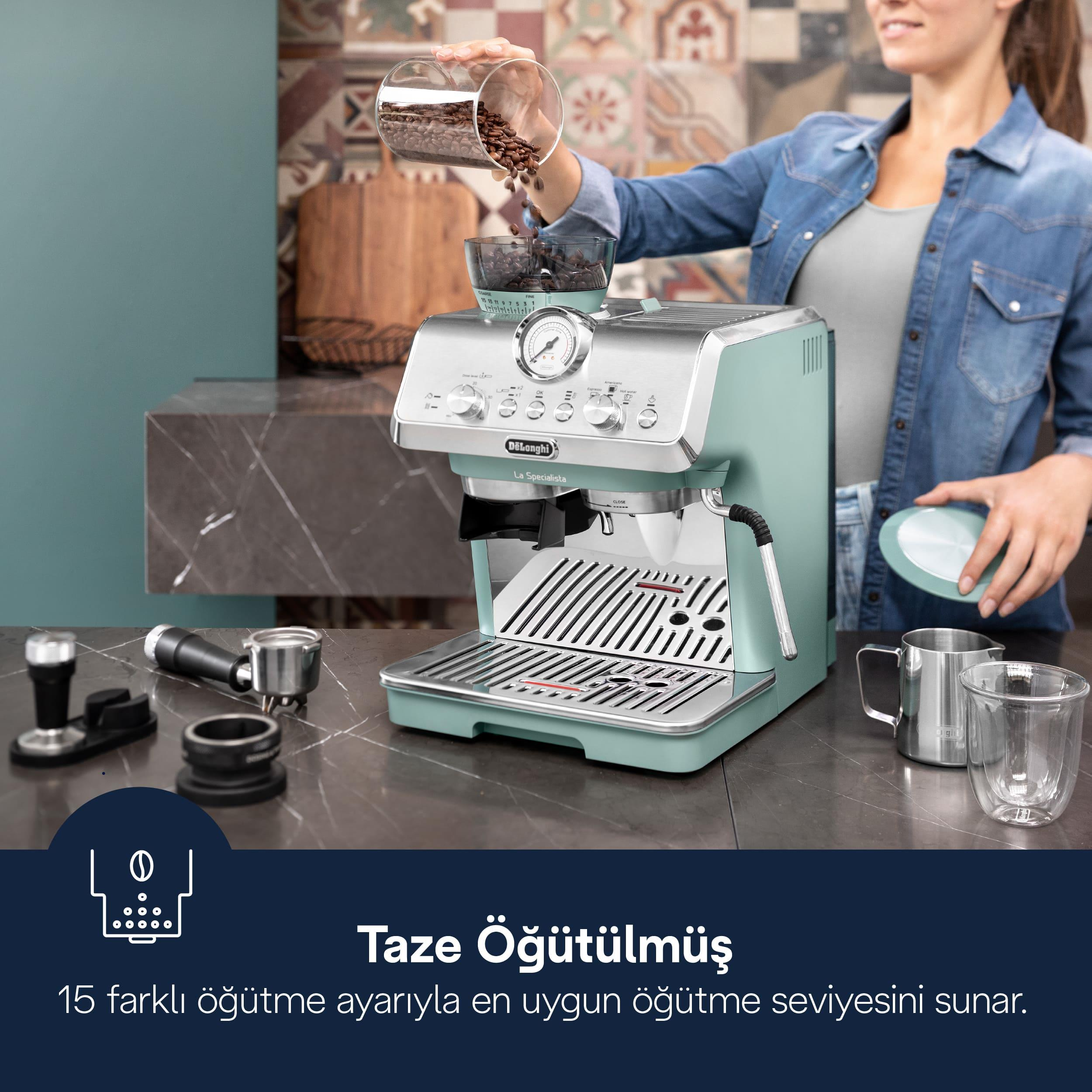 Bir kadın pastel yeşil espresso makinesinin haznesine kahve çekirdekleri döküyor.