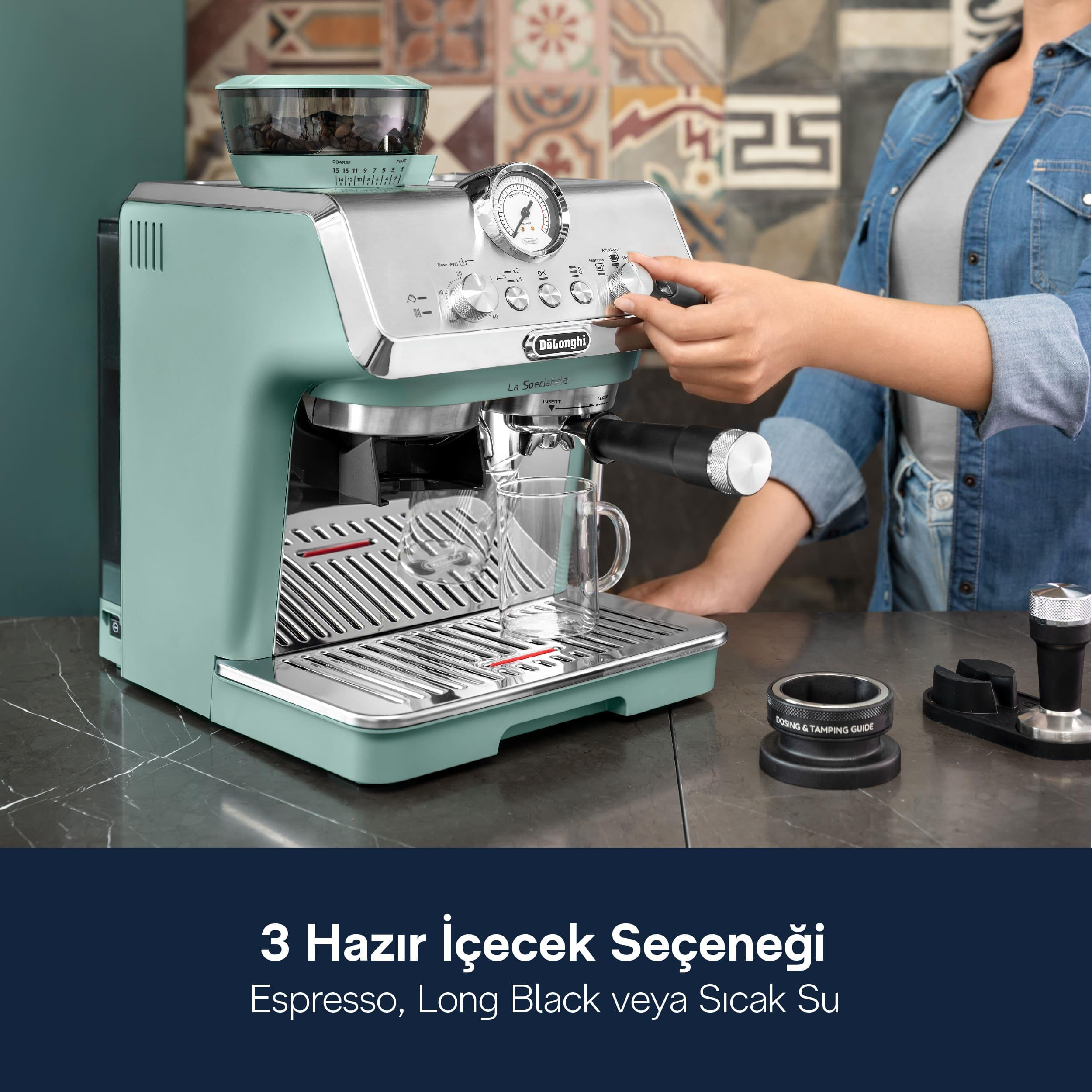 Bir kadın, mermer tezgah üzerindeki nane yeşili DeLonghi espresso makinesinin düğmesini çeviriyor.