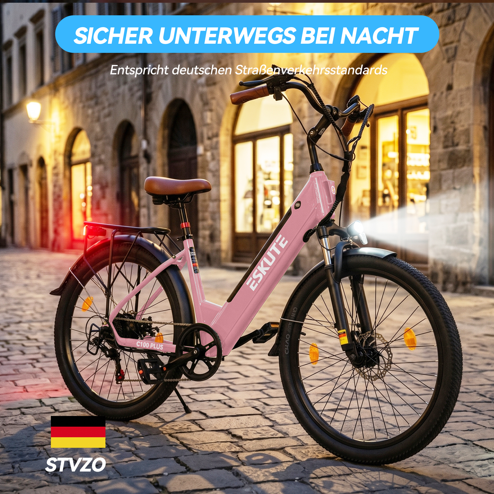Ein rosafarbenes Elektrofahrrad parkt nachts auf einer alten, gepflasterten Straße mit beleuchteten Gebäuden im Hintergrund.
