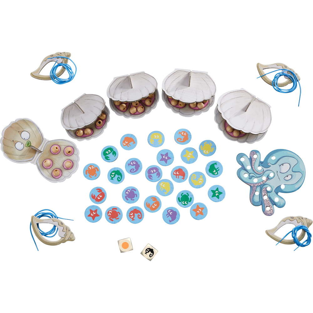 Ein Kinderspiel mit Muscheln, bunten Meerestieren, Holzperlen, blauen Schnüren und zwei Würfeln auf weißem Hintergrund.