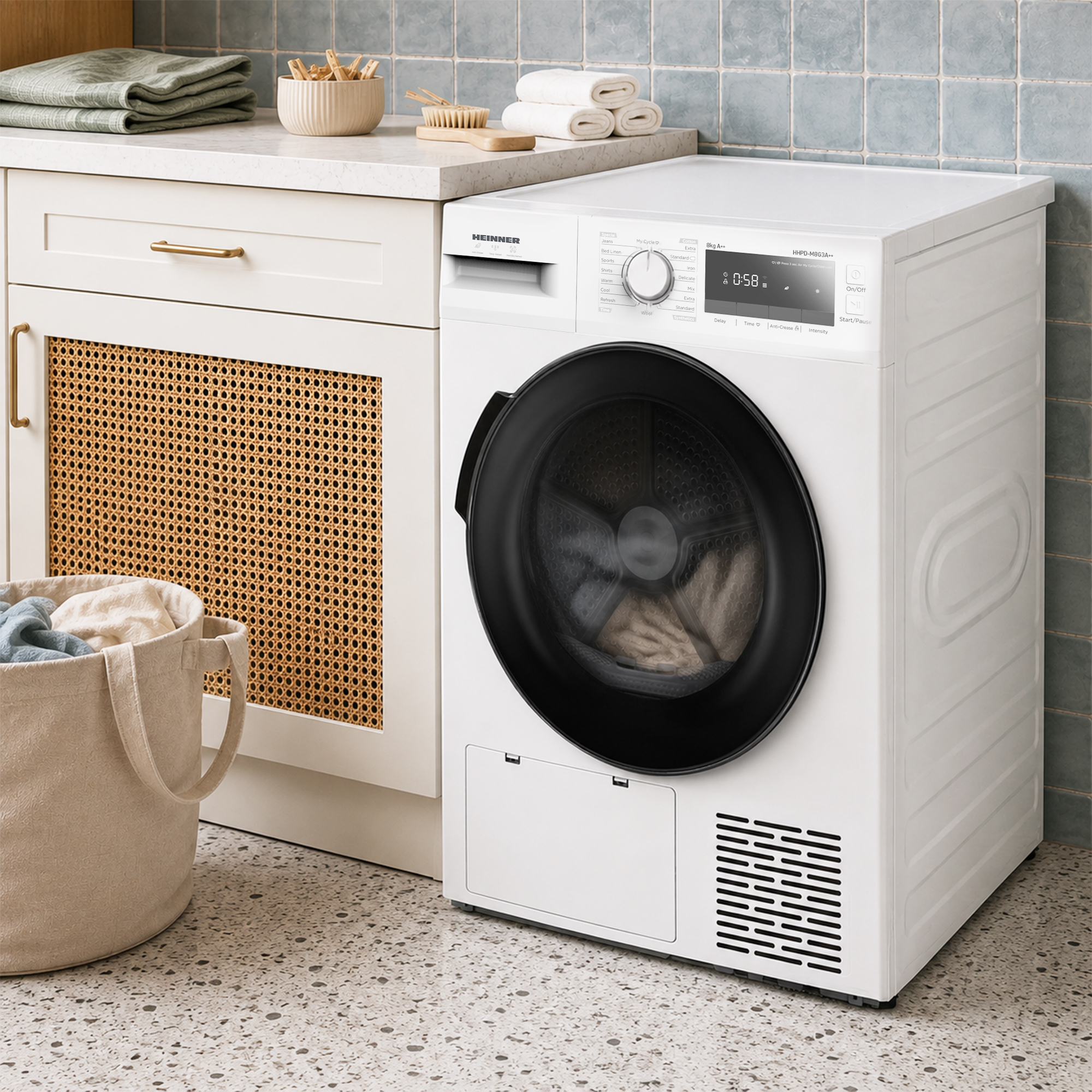 A white dryer with a black door stands next to a cabinet and a laundry basket.