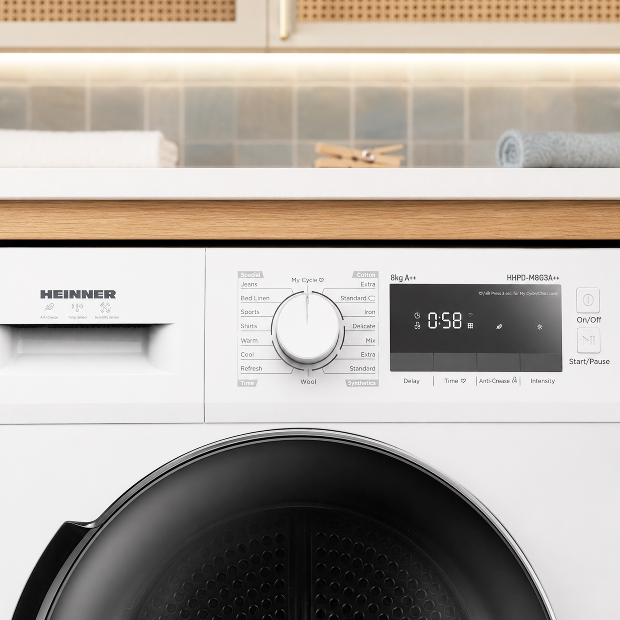 Control panel of a white Heinner tumble dryer with a dial and digital display.