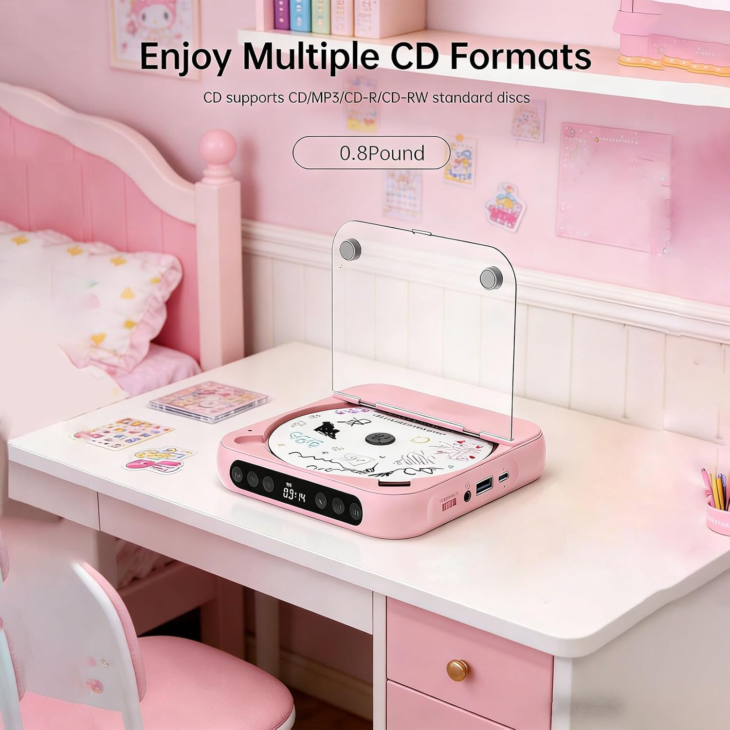 Ein rosa CD-Player steht auf einem weißen Schreibtisch in einem rosa Zimmer, mit Bett und Regal.