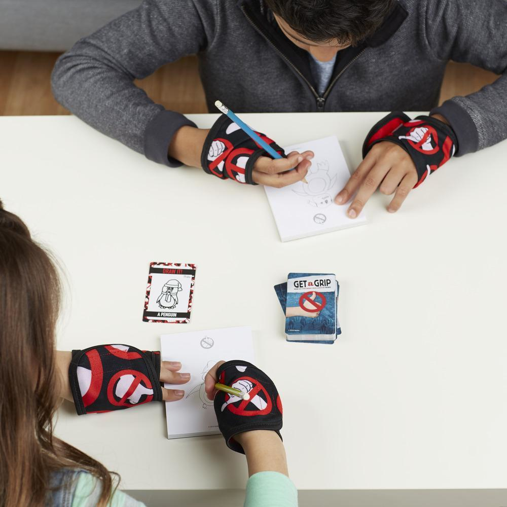 Zwei Kinder spielen ein Malspiel an einem weißen Tisch, tragen Handgelenkbandagen und halten Stifte mit Mühe.