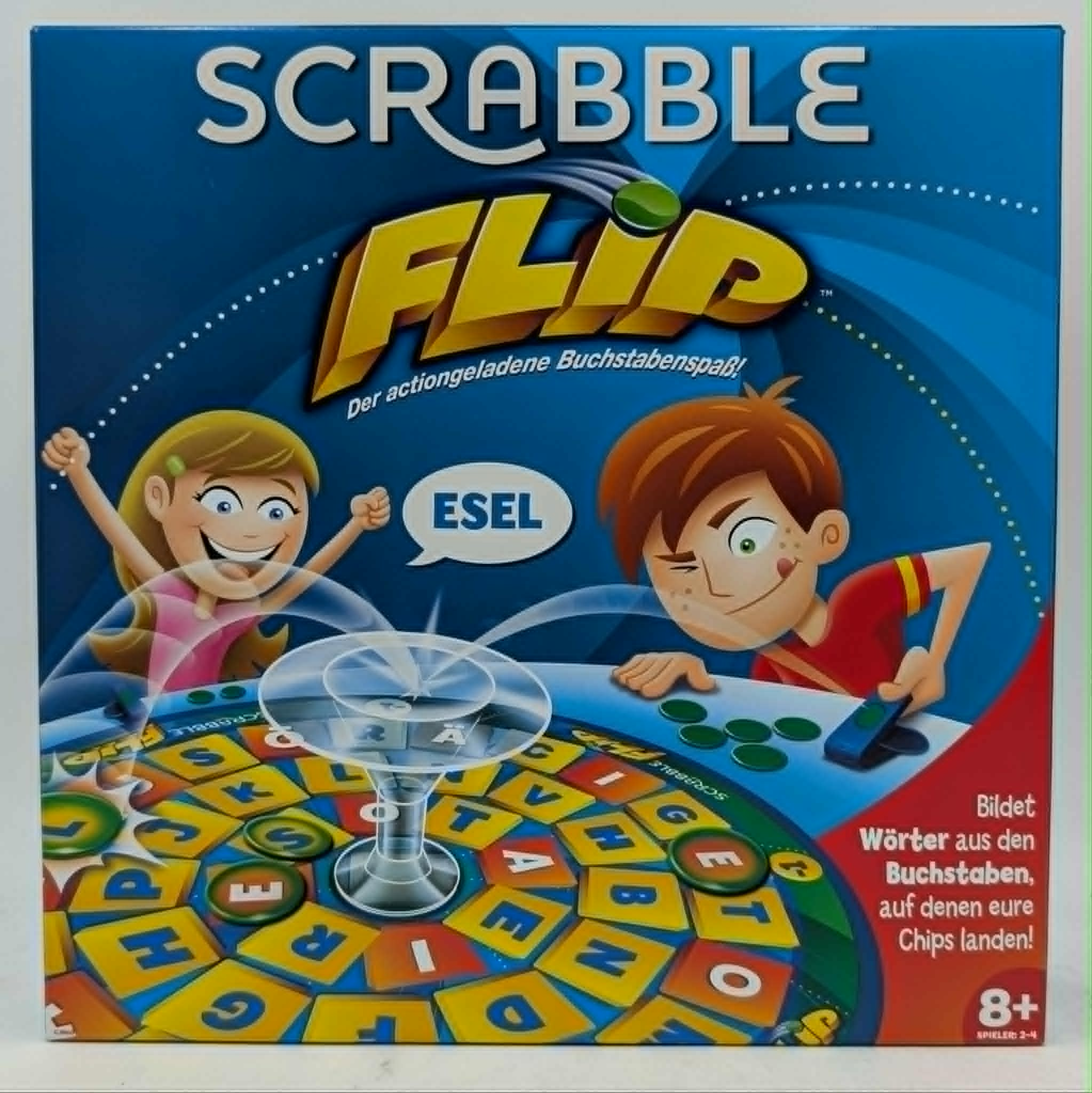 Die Spielverpackung von Scrabble Flip mit lachenden Kindern, bunten Buchstaben und einer Torschussvorrichtung.